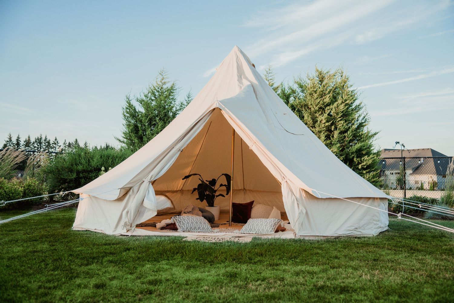 A spacious white glamping tent with a dog resting inside on a sunny day.