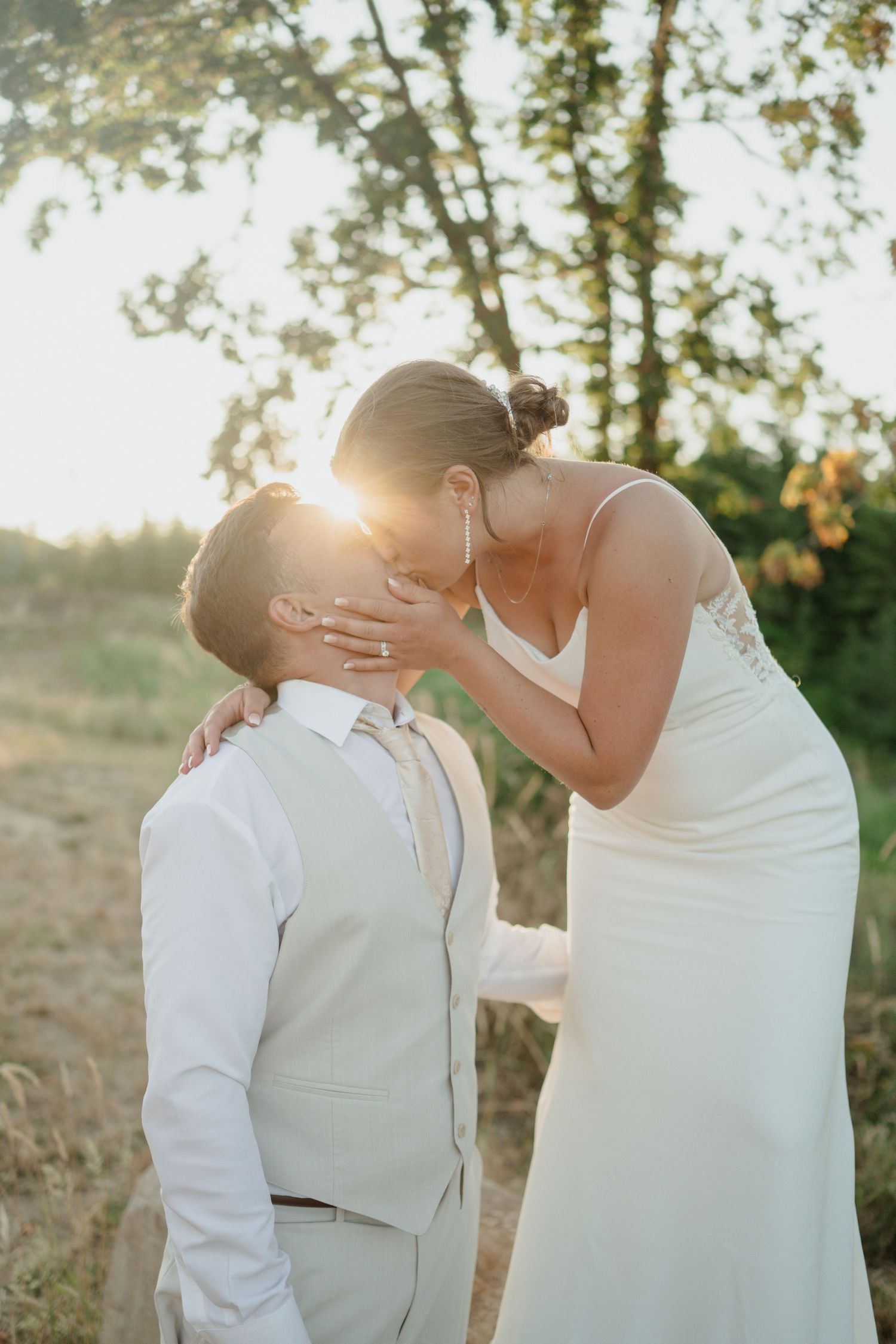 An intimate wedding moment captured against a sunset-lit natural backdrop.
