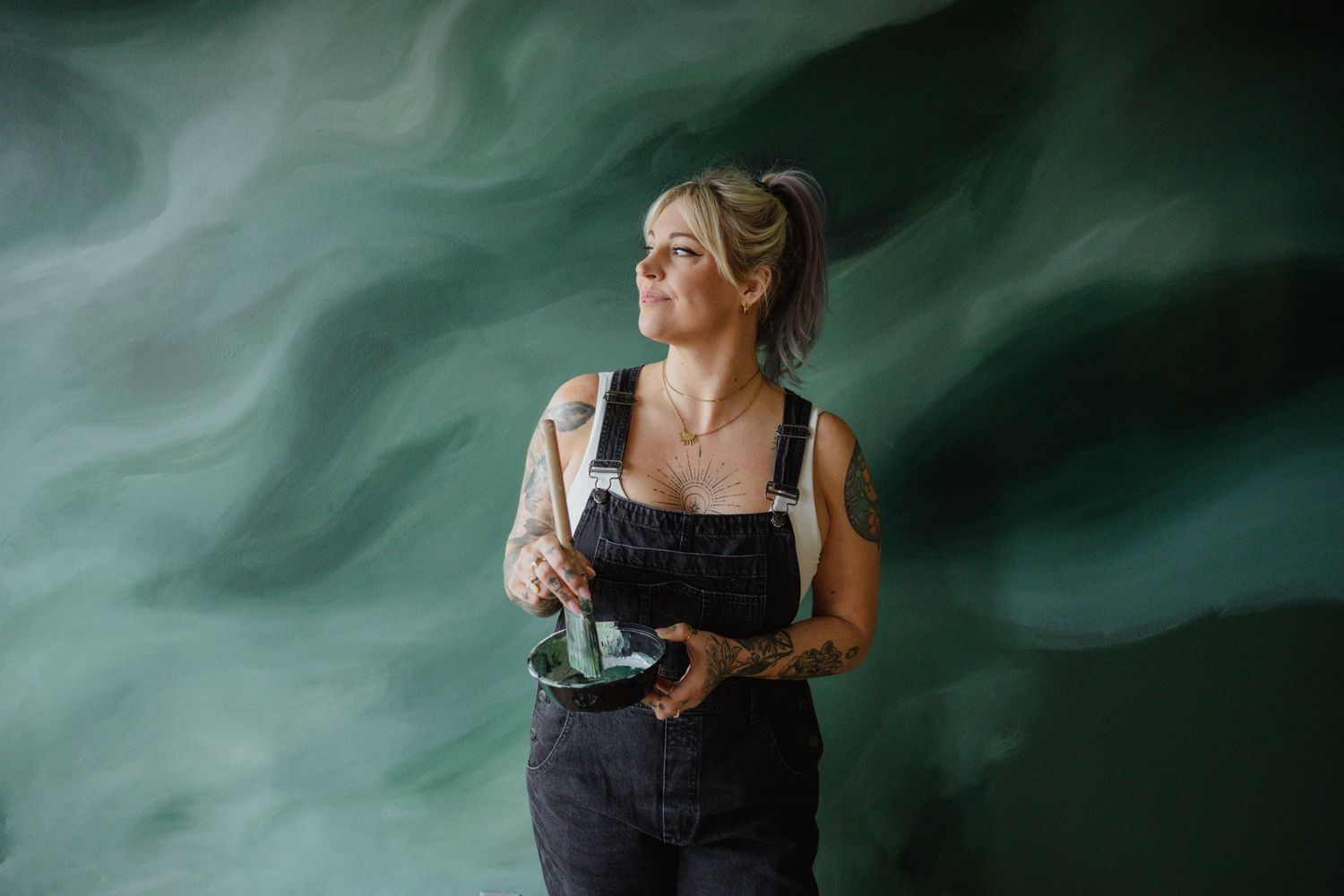 An artist working with paint against a swirling green background.