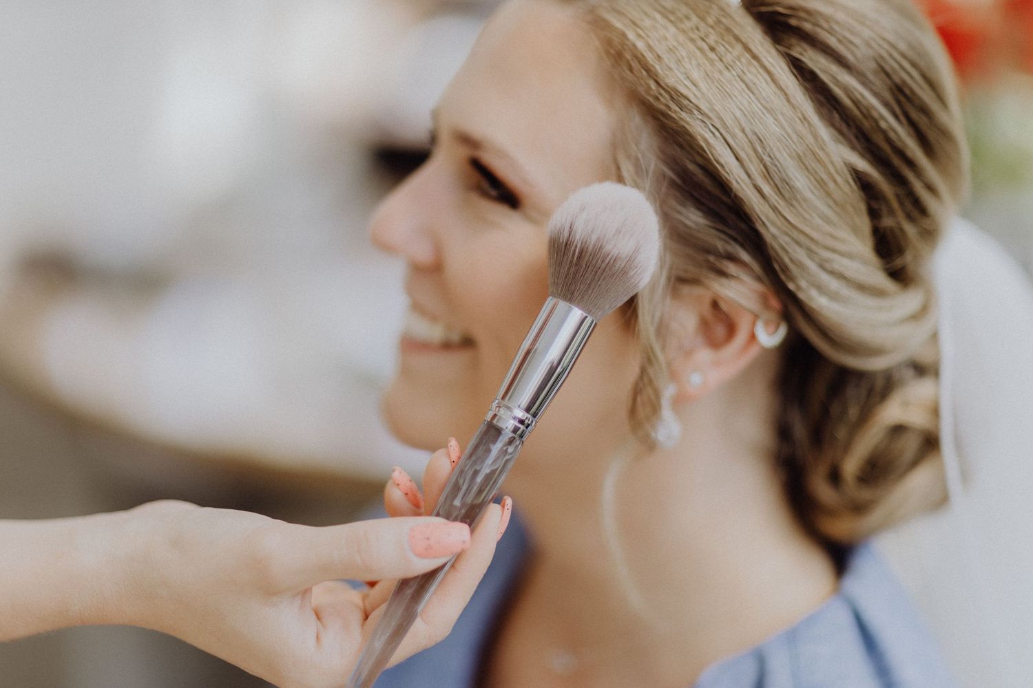 Ein Maskenbildner trägt während der Hochzeitsvorbereitungen Kosmetik mit einem Pinsel auf.