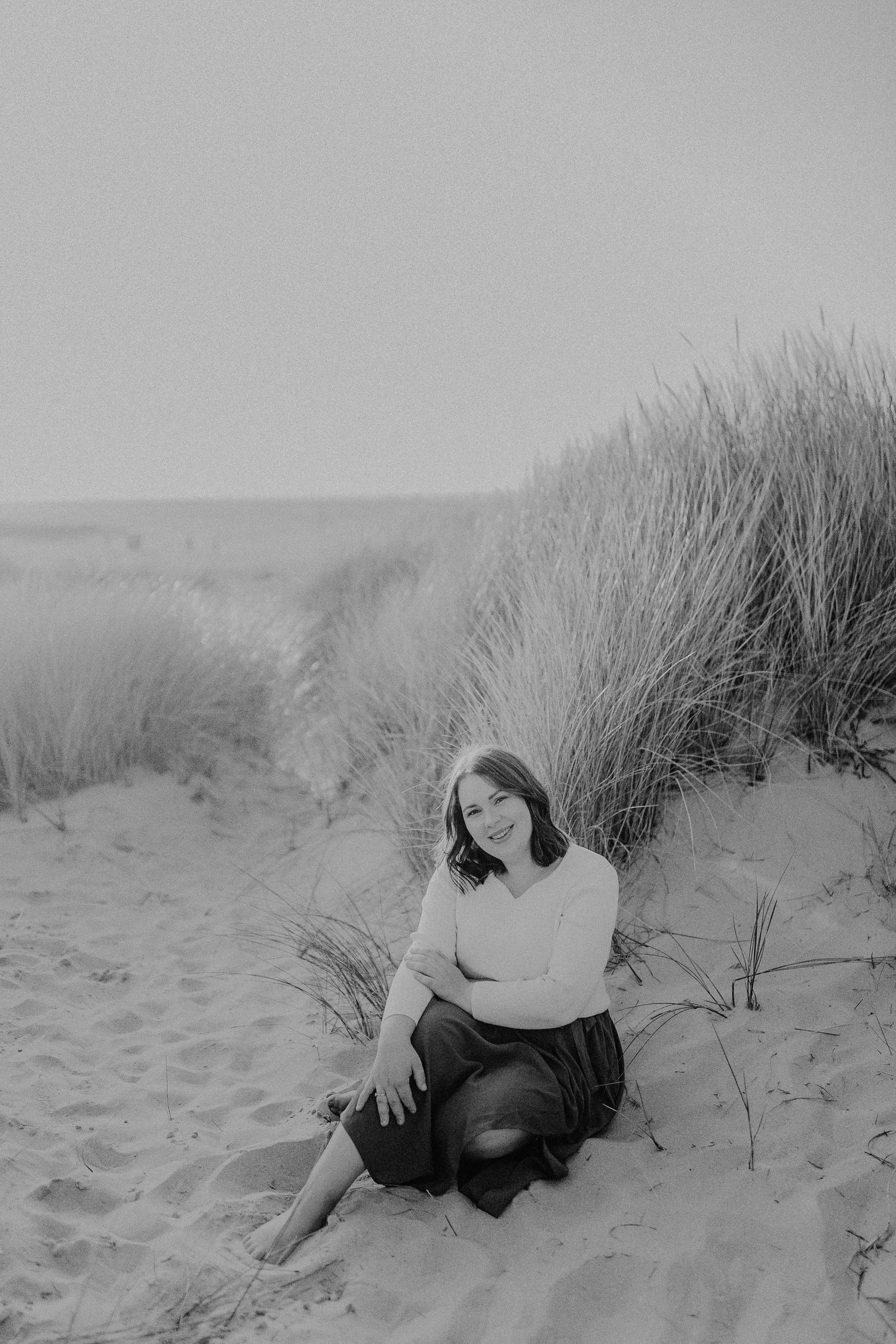 Ätherisches Graustufenporträt an einem Sandstrand mit Küstenvegetation, die eine verträumte Atmosphäre schafft in Sankt Peter Ording.