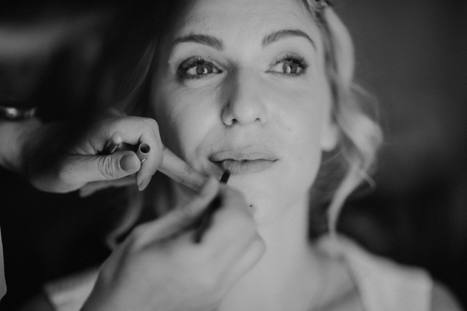 Schwarz-Weiß-Porträt während der Hochzeits-Make-up-Anwendung.
