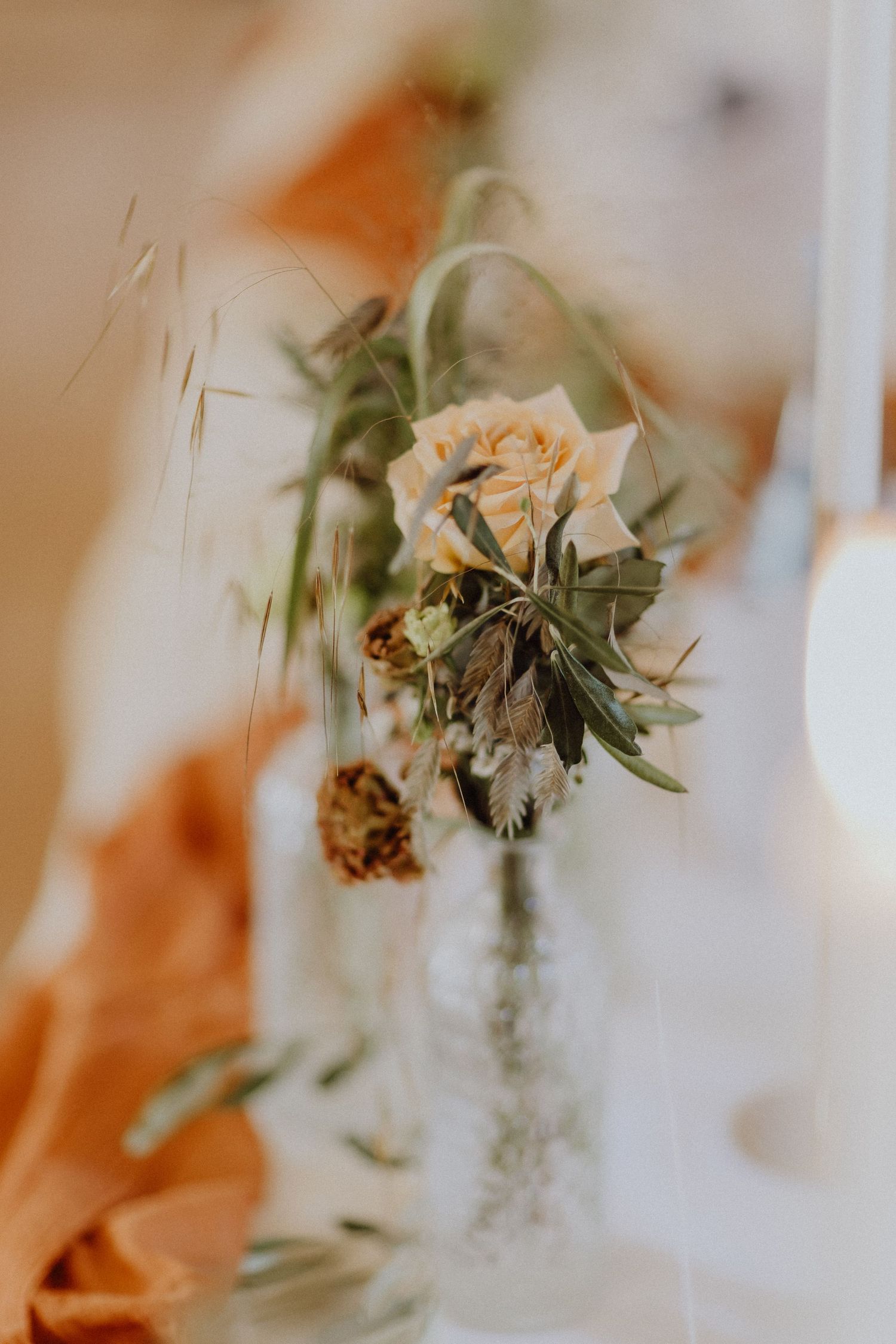 Romantisches Blumenarrangement mit getrockneten Rosen und Grün in Vintage-Glasflasche.