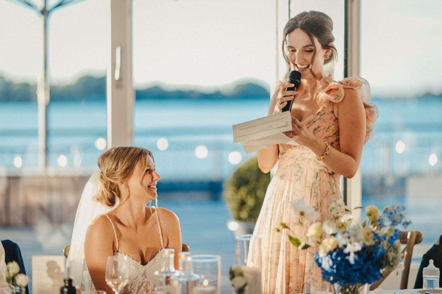 Hochzeitsempfang im Freien am Wasser mit einer Rede während der goldenen Stunde.