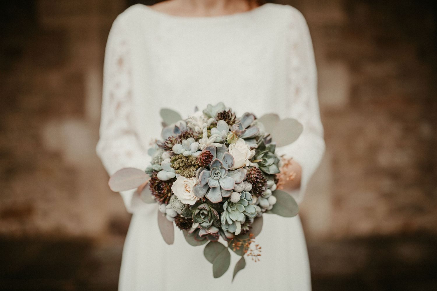 Braut hält eleganten Winterstrauß mit weißen Blumen und salbeigrünen Eukalyptusblättern in Braunschweig.