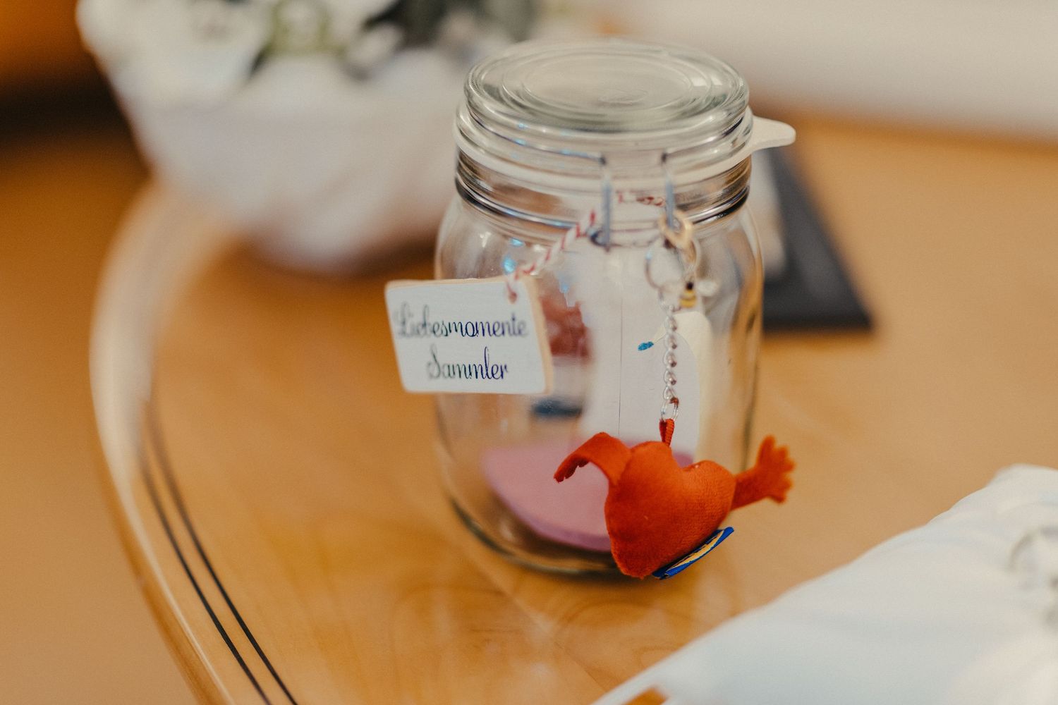 Glasgefäß mit dekorativem orangefarbenem Fisch auf Holztisch beim Hochzeitsempfang.