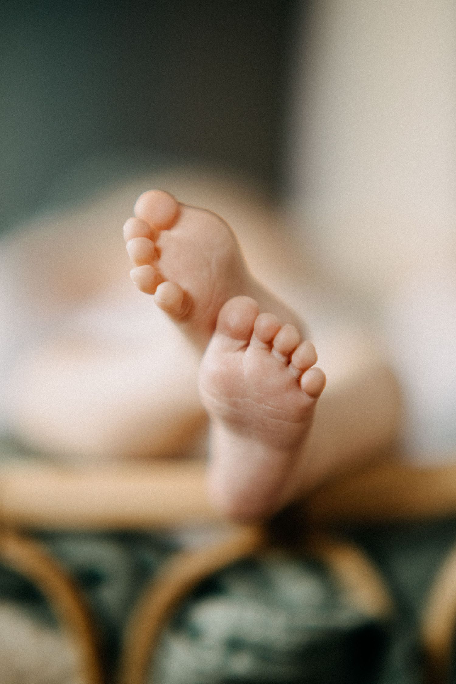 Nahaufnahme von winzigen Babyfüßen vor weichem unscharfem Hintergrund.