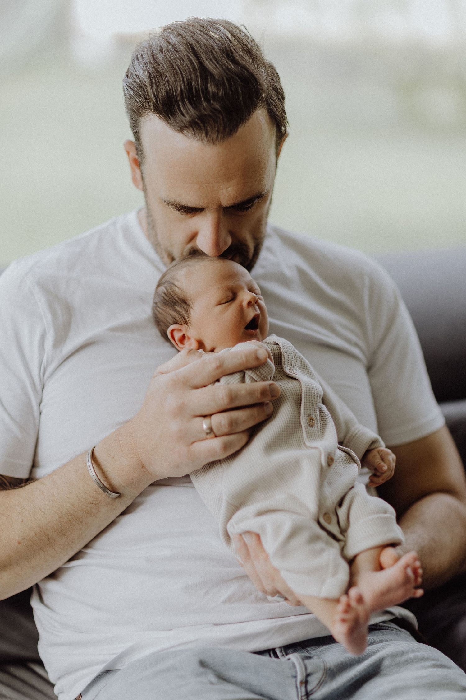 Zärtlicher Moment zwischen Papa und neugeborenem Baby in heller Tönen.