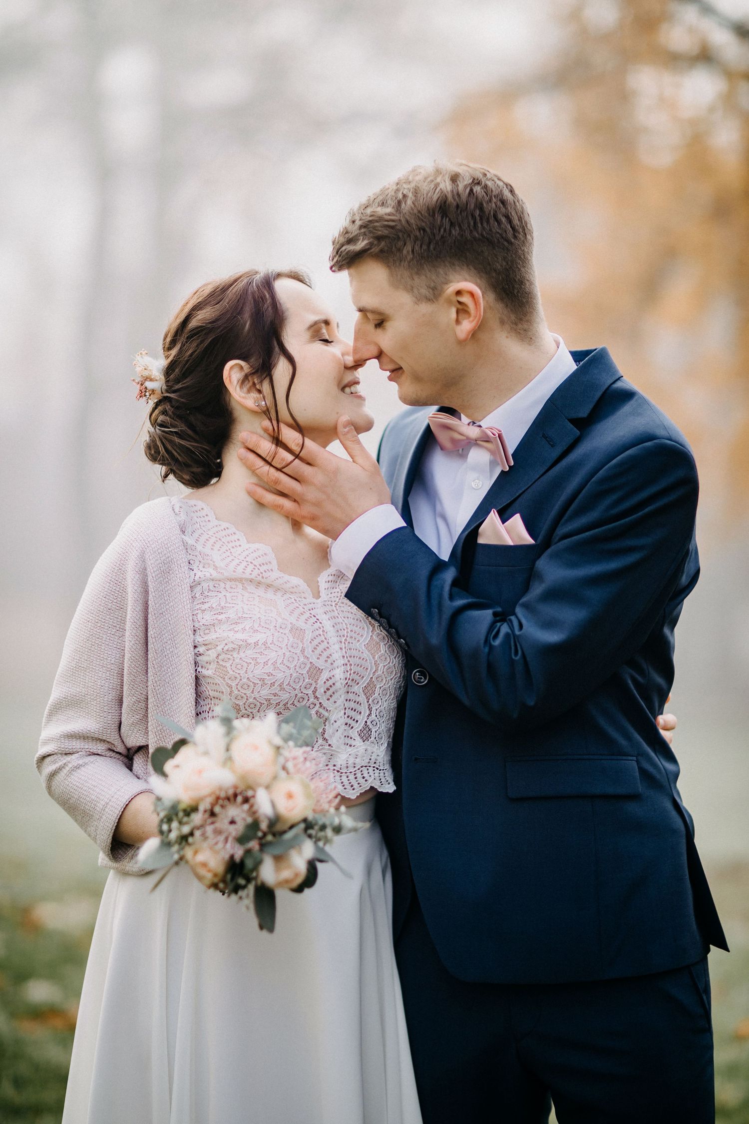 Ein romantisches Hochzeitspaar teilt einen intimen Moment im Winter mit der Braut, die einen zarten Blumenstrauß hält.