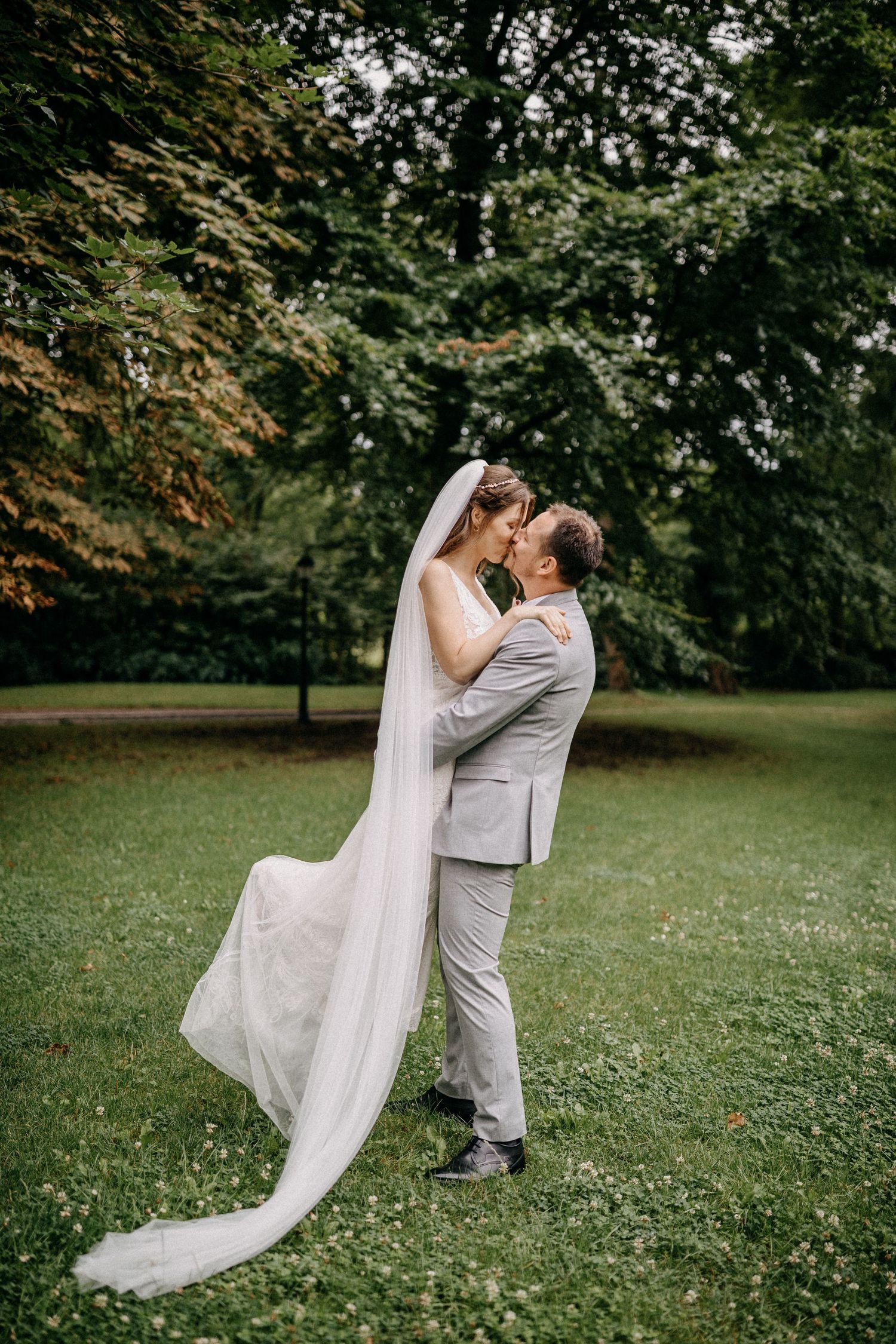Brautpaar teilt einen romantischen Moment in einer üppigen Gartenumgebung mit fließendem weißem Hochzeitskleid und Schleier in Aschersleben.