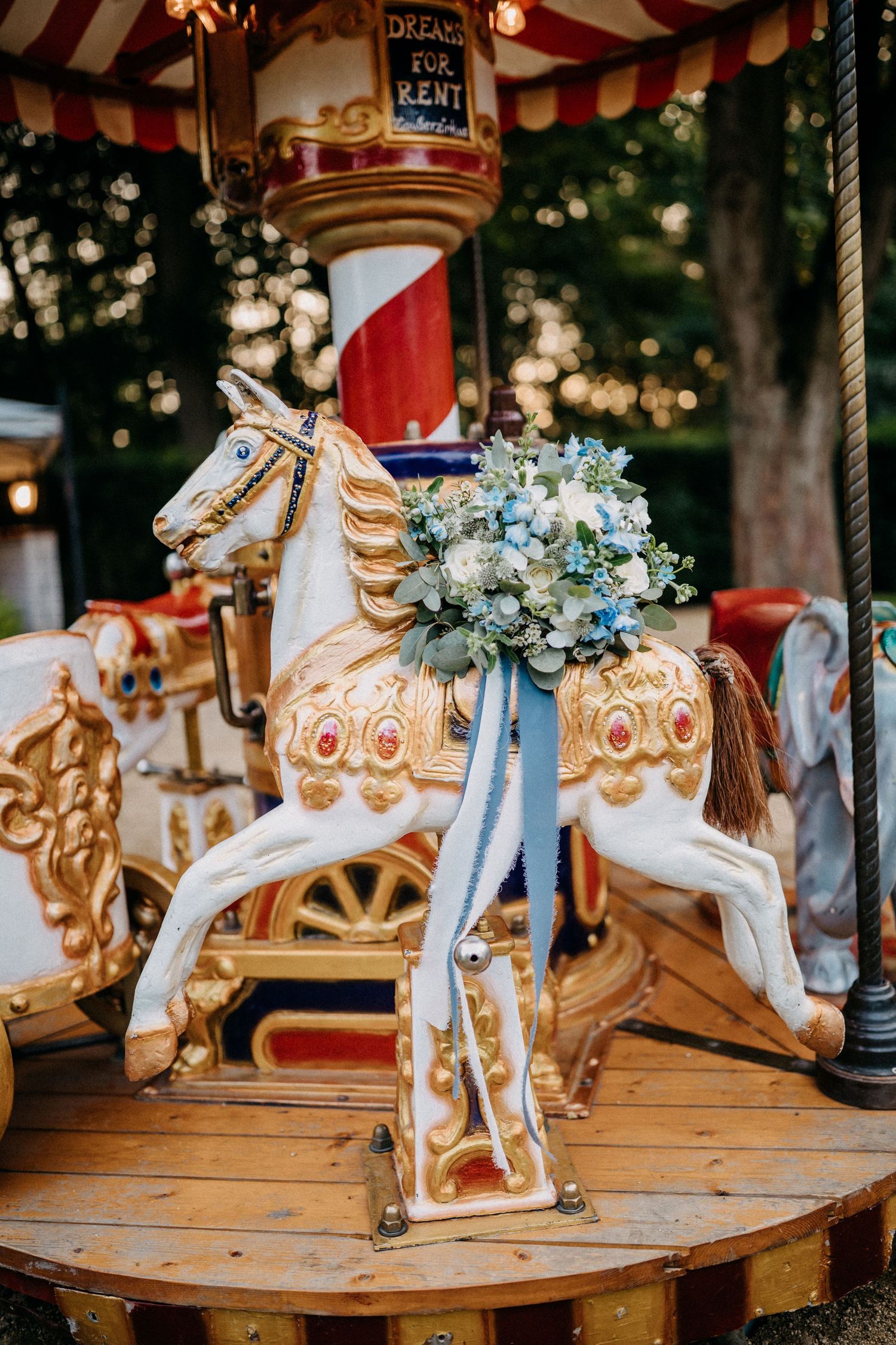 Vintage-Karussellpferd, verziert mit zartem blau-weißem Blumenarrangement.