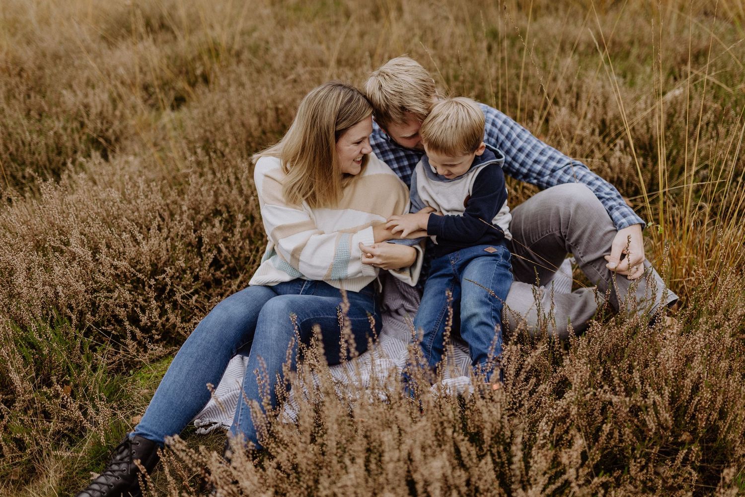 Familie sitzt an einem Herbstnachmittag zusammen im hohen goldenen Gras in Gifhorn.