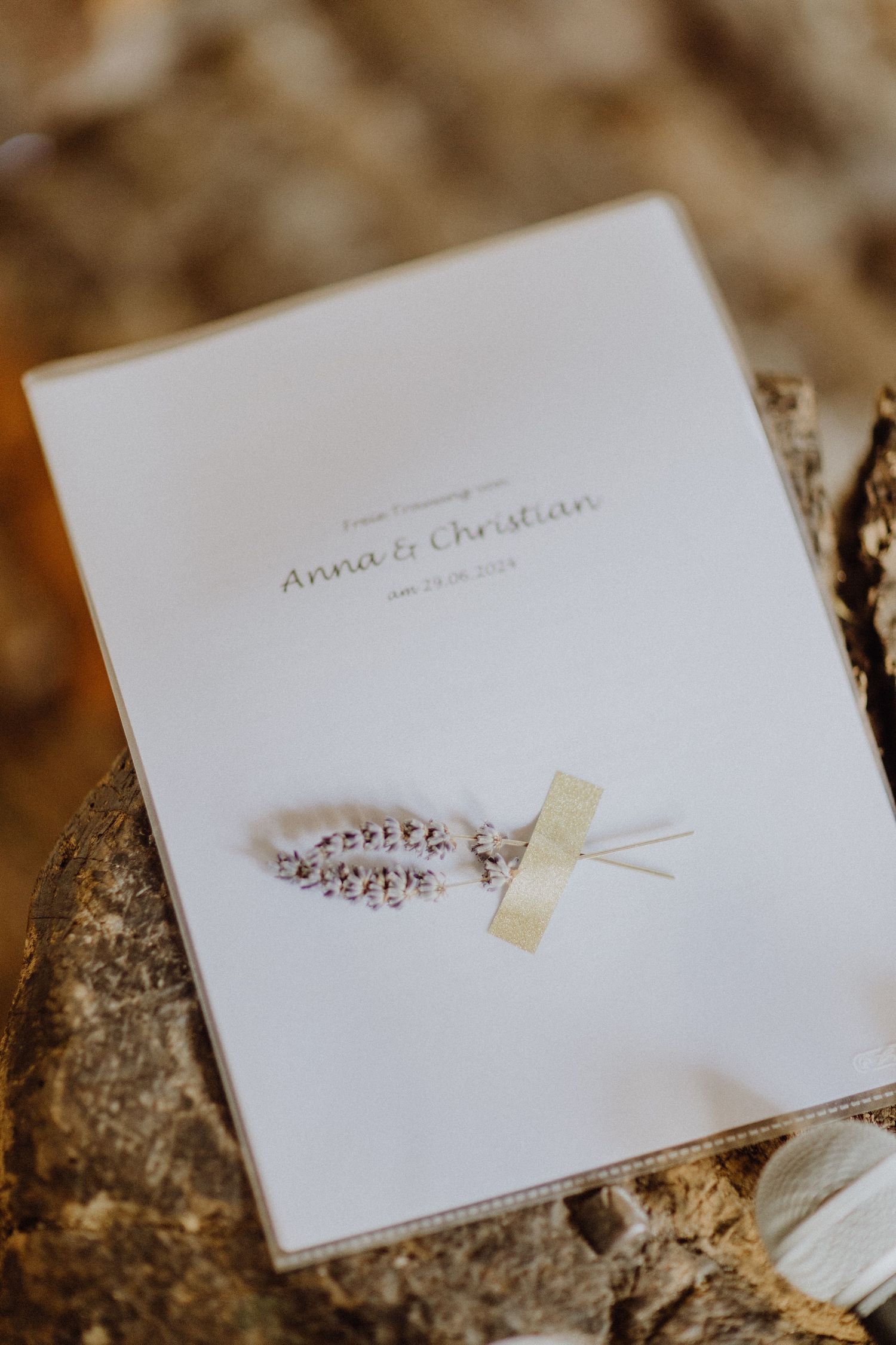 Ein elegantes weißes Hochzeitsprogramm mit Namen auf einer strukturierten Oberfläche.