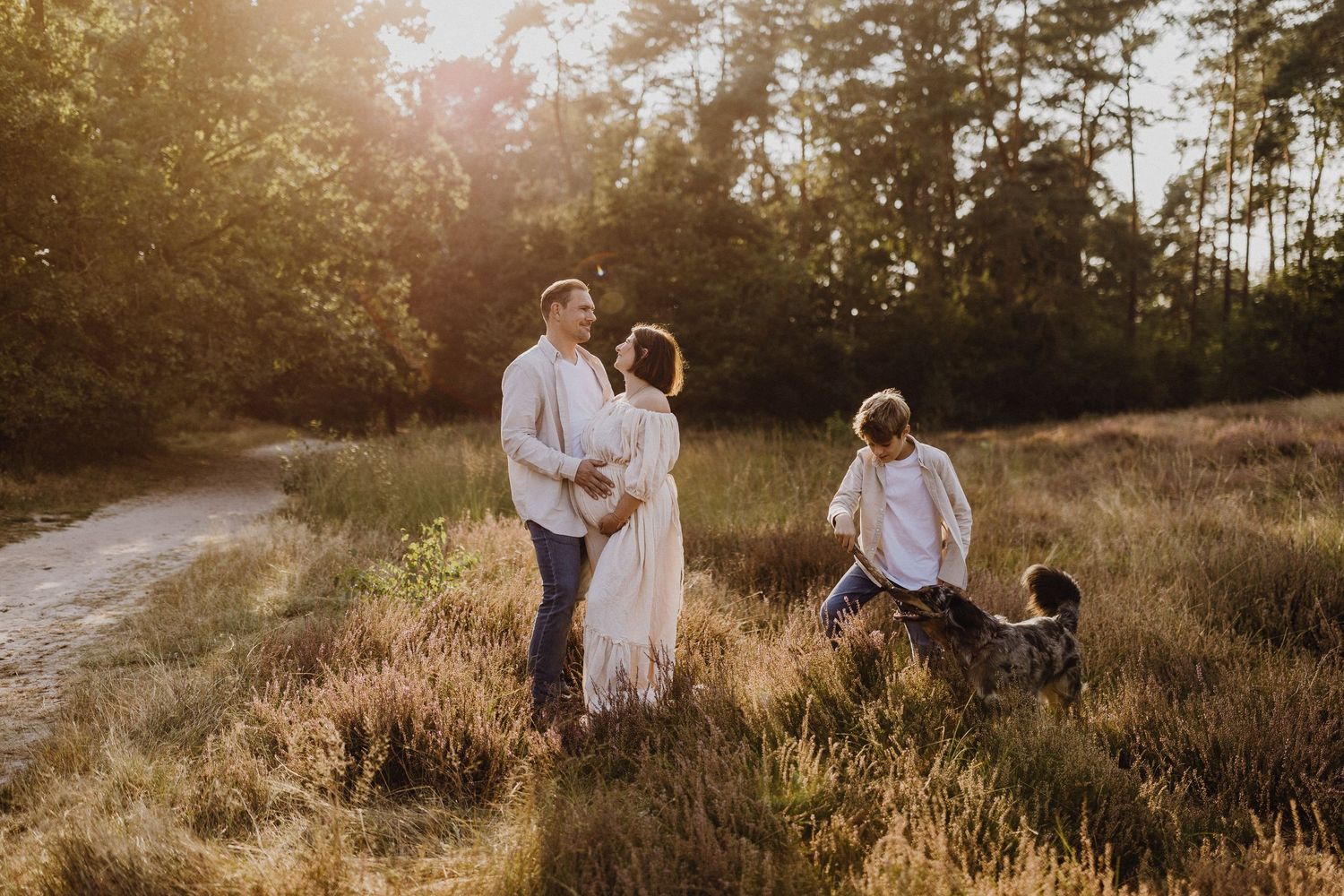 Familie posiert zusammen auf einem sonnenbeschienenen Feld zur goldenen Stunde.