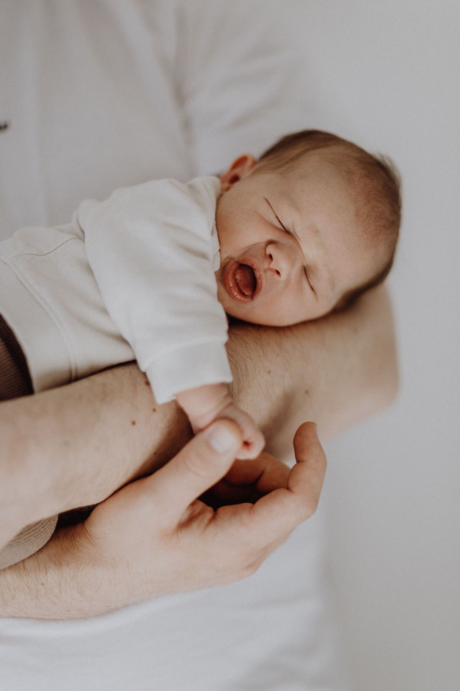 Das schlafende Baby gähnt, während es sanft umarmt wird.