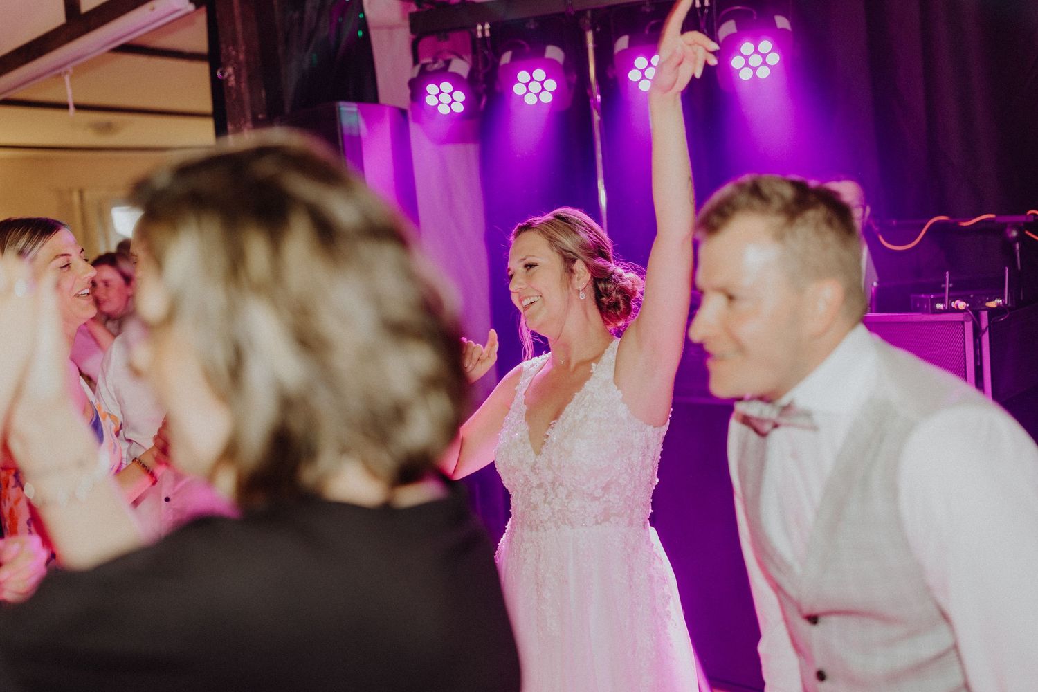 Hochzeitsfeier auf der Tanzfläche mit lila Beleuchtung und Partyatmosphäre.