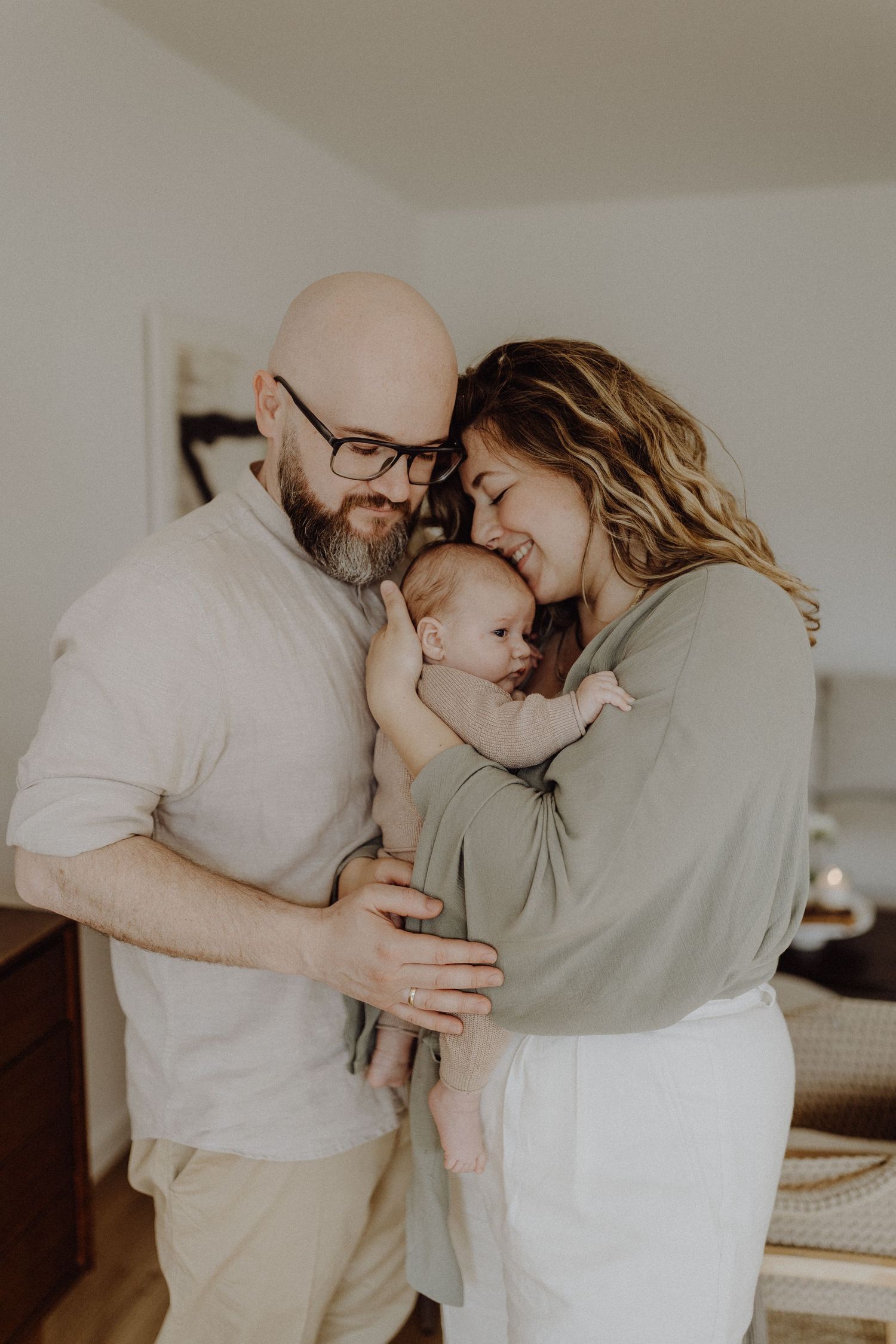 Intimes Familienporträt mit Neugeborenen in einer minimalistischen Innenumgebung.
