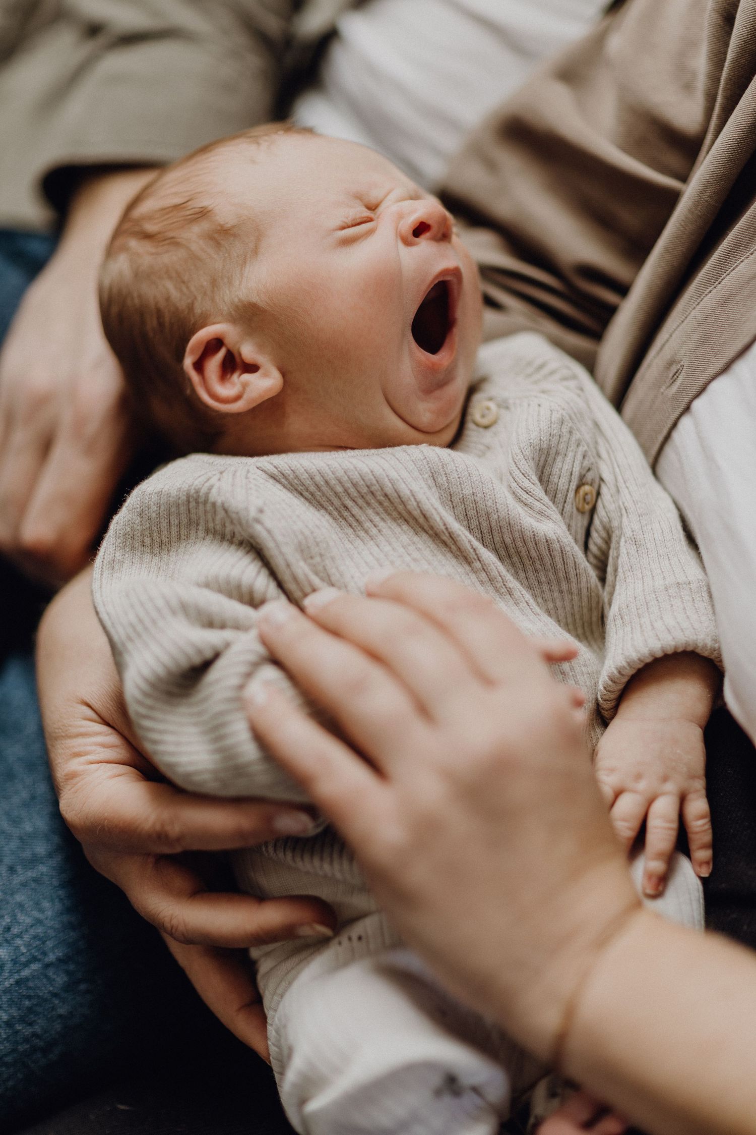 Neugeborenes Baby gähnt, während es einen kuscheligen Strickpullover trägt.