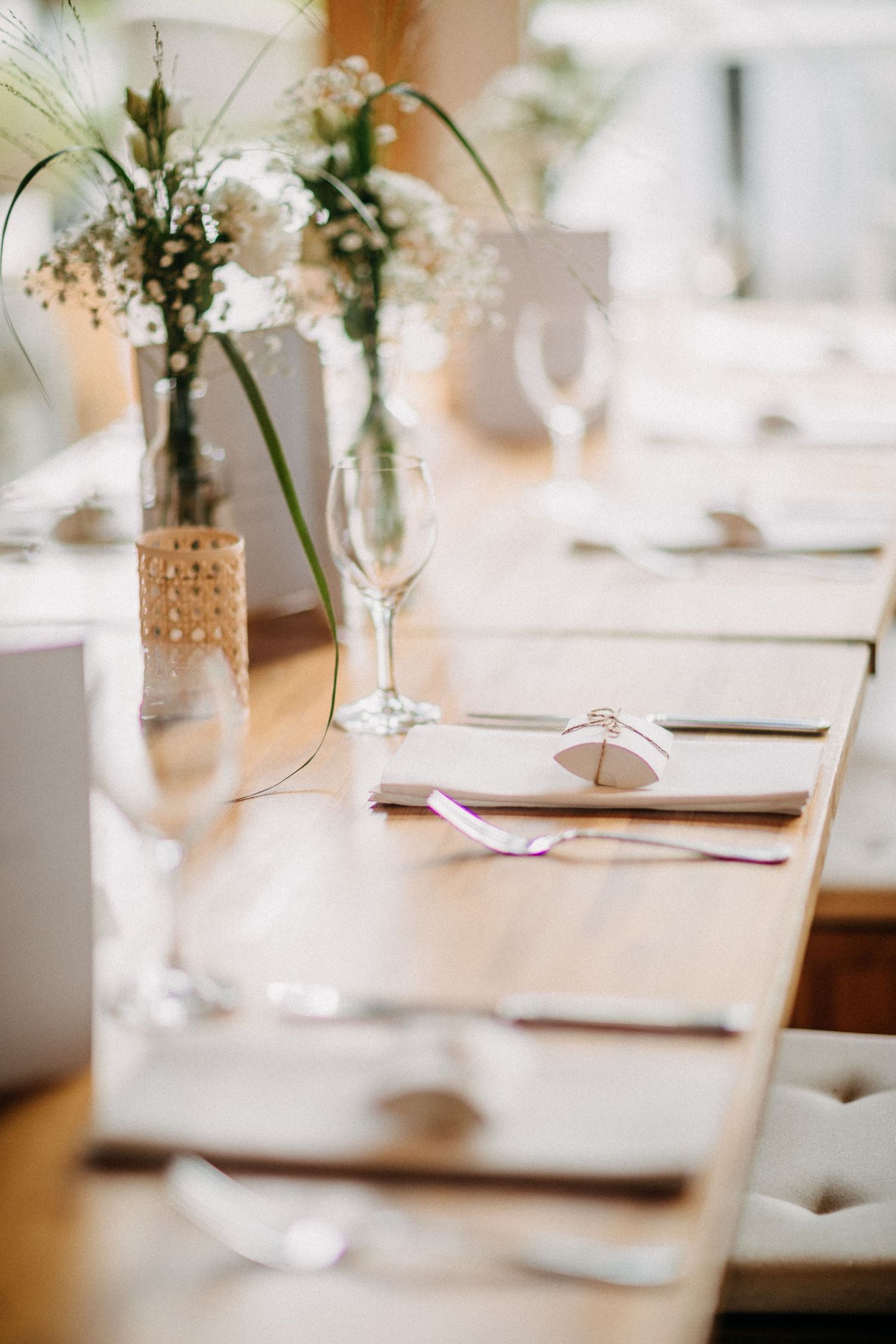 Elegante Tischdekoration mit zarten floralen Mittelstücken und Weingläsern für den Hochzeitsempfang.