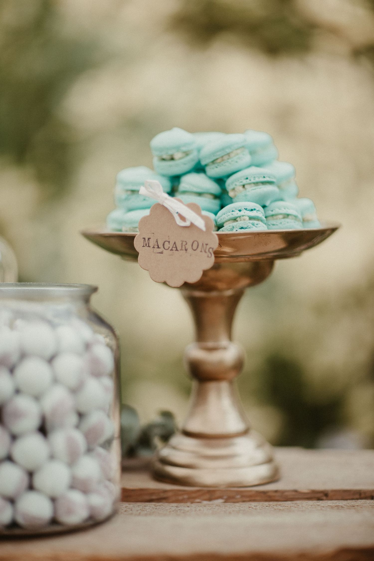 Hellblaue Macarons auf Vintage-Gold-Kuchenständer mit Etikett.