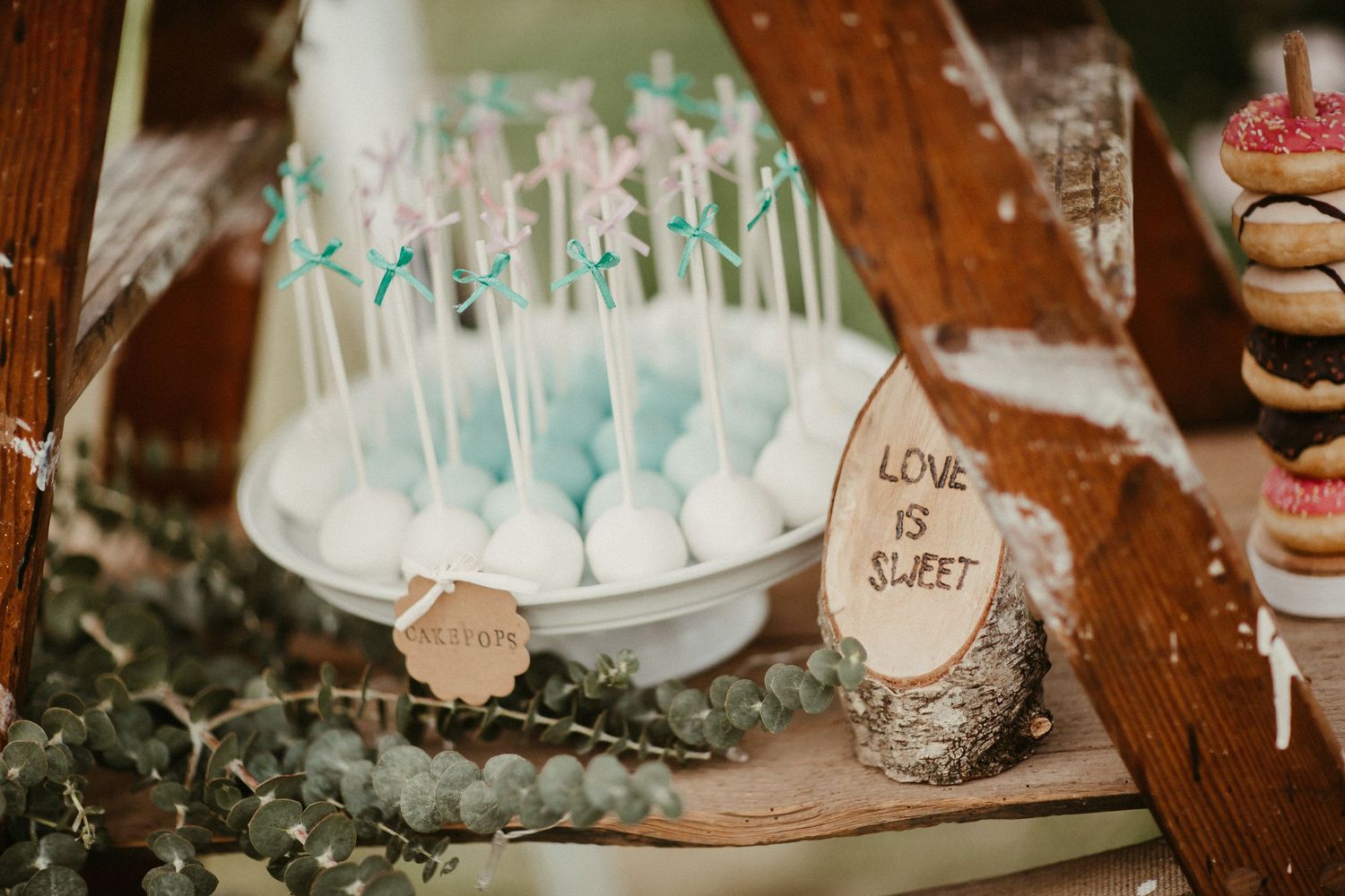 Blaue Kuchen-Pops und Dessert-Display mit rustikalem Holzdekor bei der Hochzeit.