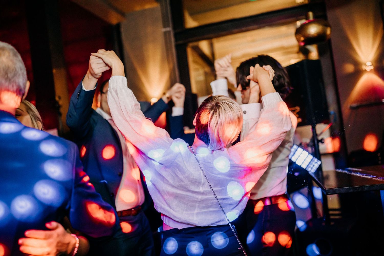 Hochzeitsempfang-Tanzfläche gefüllt mit Menschen, die unter bunten Partylichtern feiern.