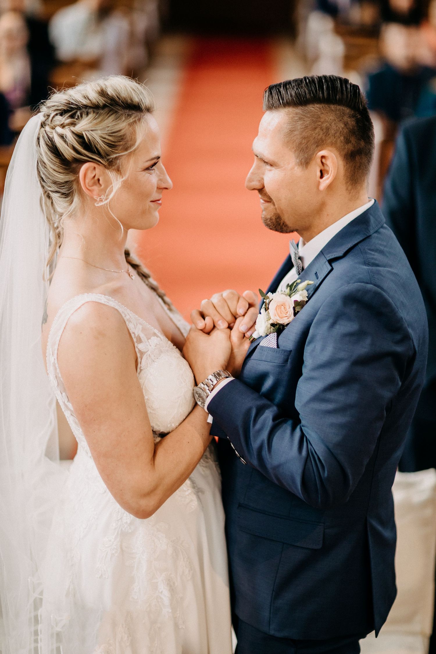 Paar in Hochzeitskleidung hält Händchen während des intimen Zeremonienmoments.