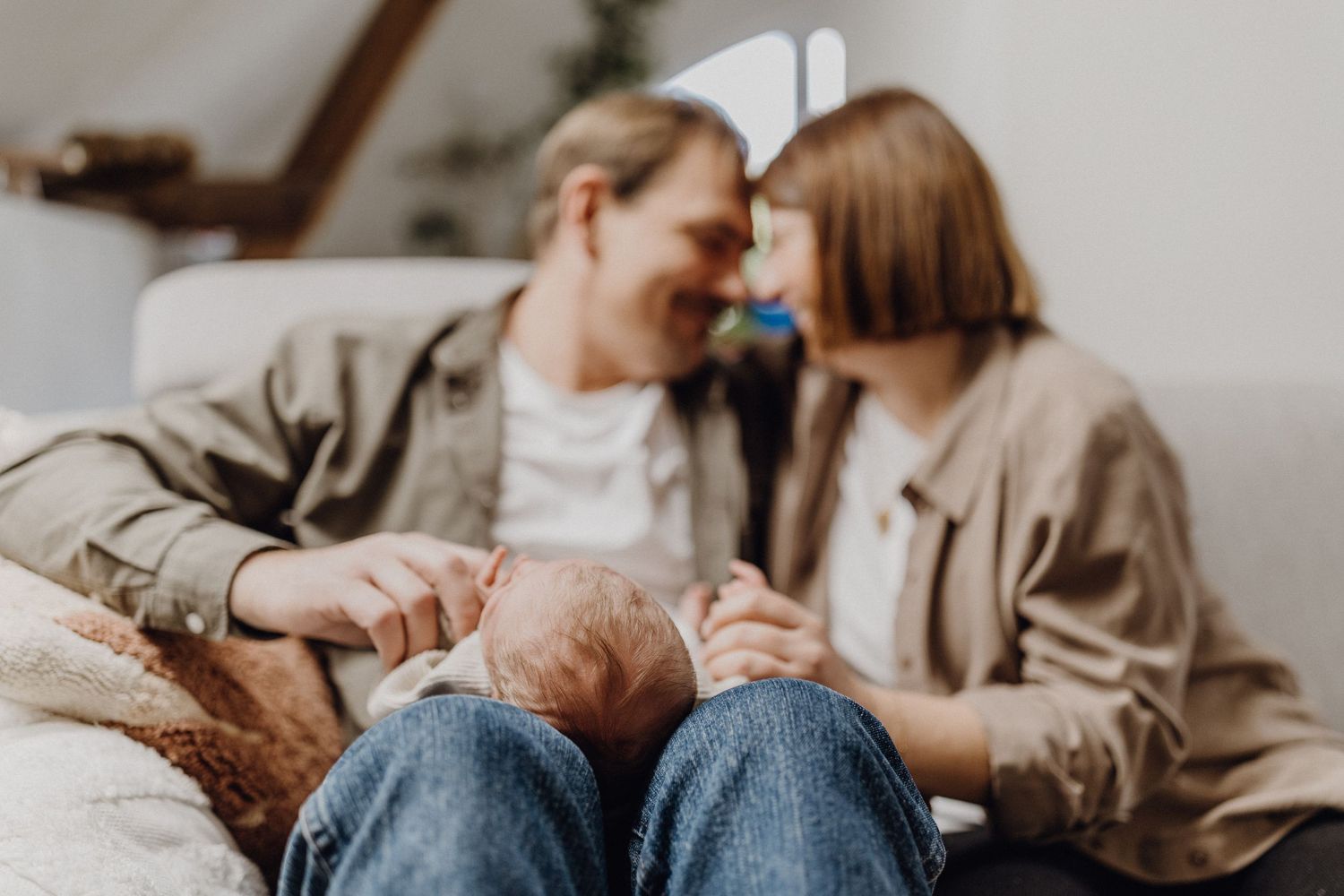 Intimer Familienmoment auf der Couch mit neuem Baby in einer lässigen häuslichen Umgebung.