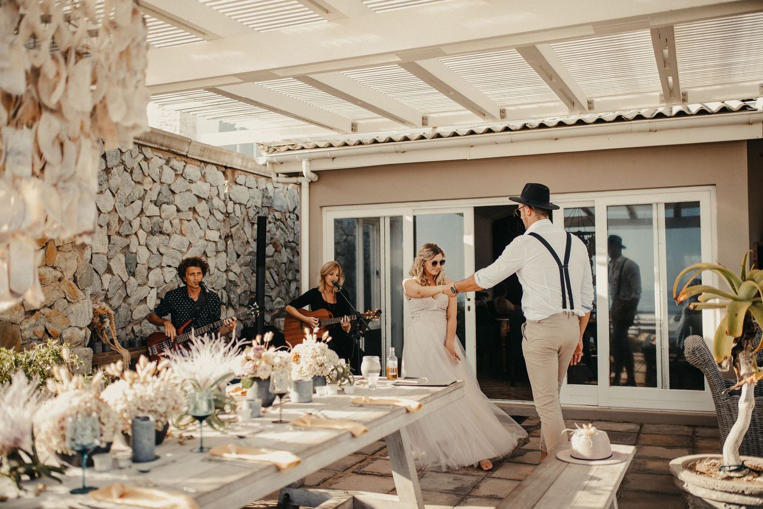 Hochzeitsempfang im Freien mit Gästen, die an einem elegant dekorierten Tisch speisen.