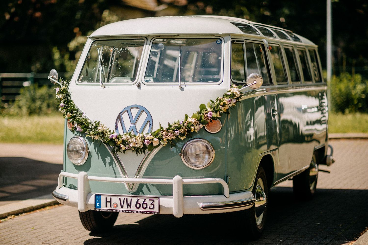 Klassischer VW-Bus mit Blumengirlande für eine Hochzeitsfeier verziert.