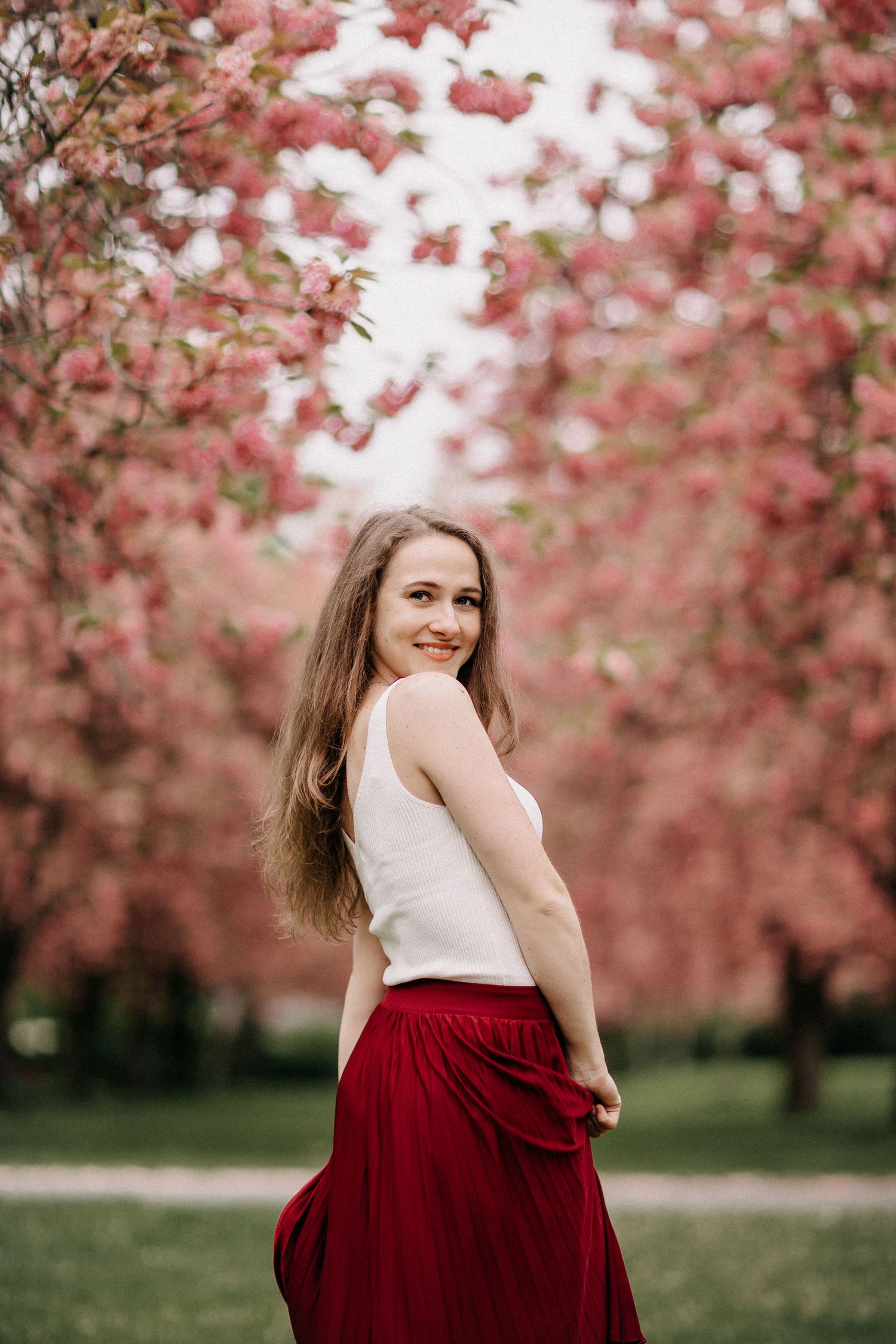 Eine Person in einem roten Rock wirbelt im Frühling zwischen blühenden Kirschblütenbäumen.