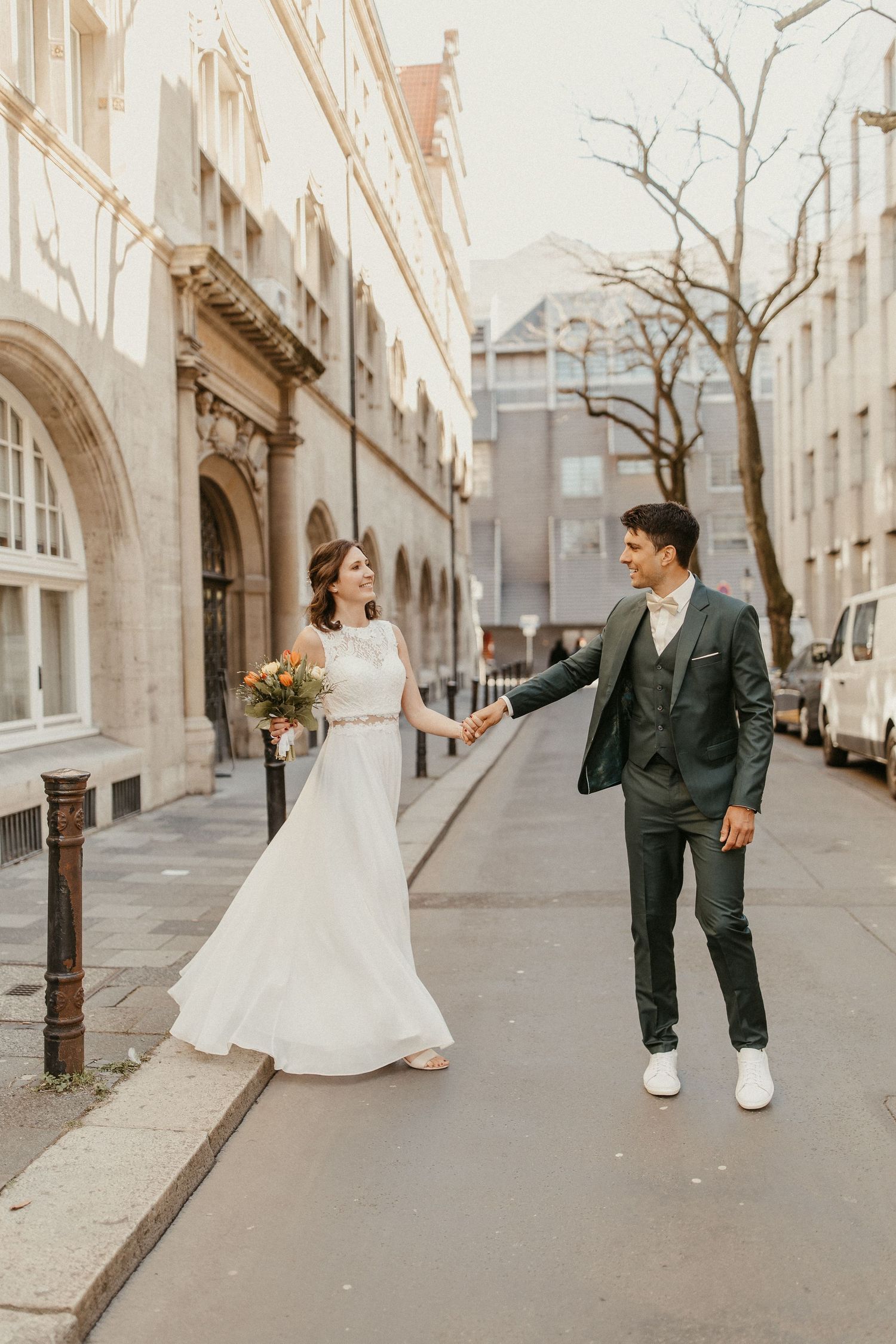 Ein Hochzeitspaar, das entlang einer charmanten Stadtstraße mit klassischer Architektur geht in Braunschweig.
