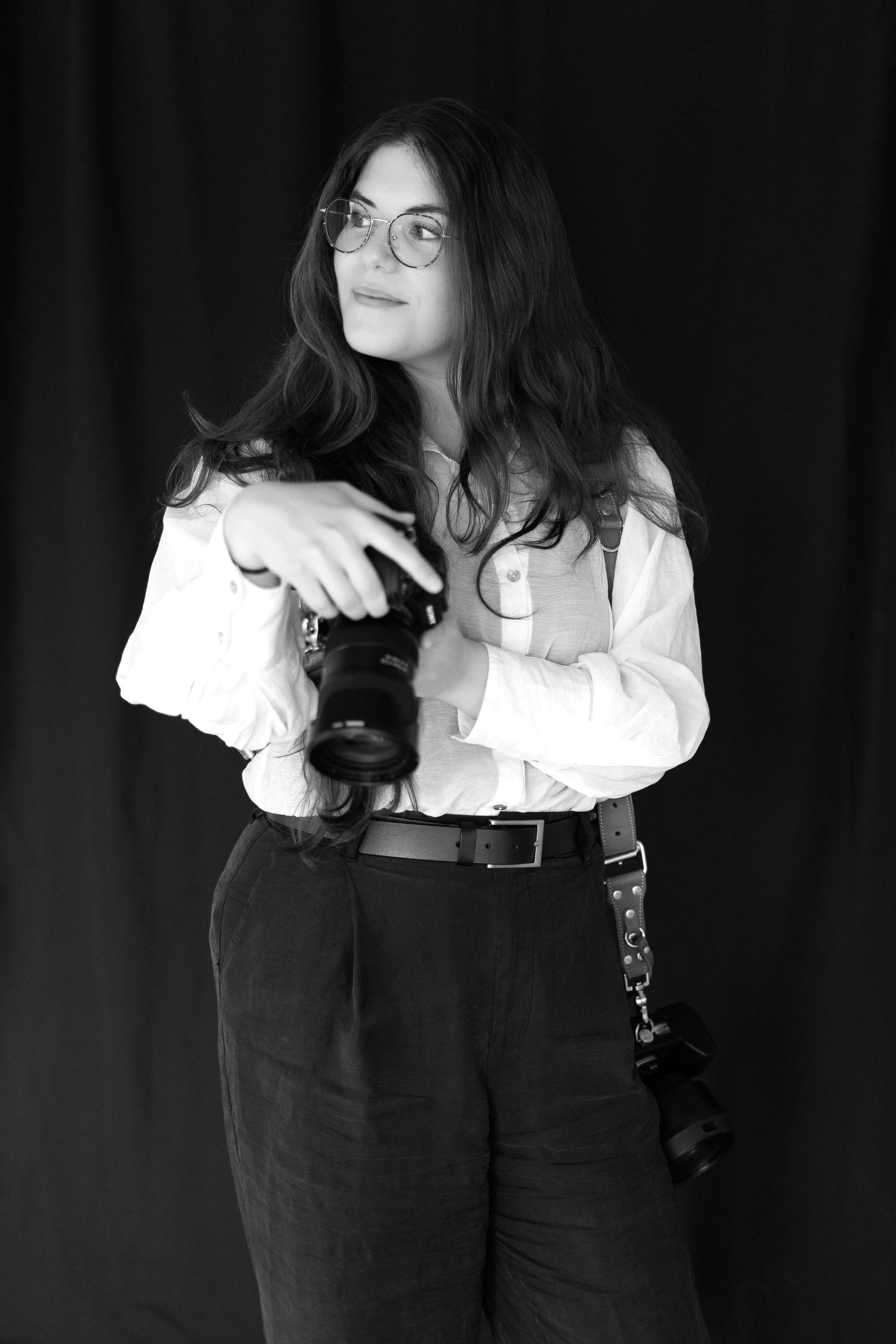 A black and white portrait series shows someone wearing glasses, a white blouse and dark suspenders in artistic poses.