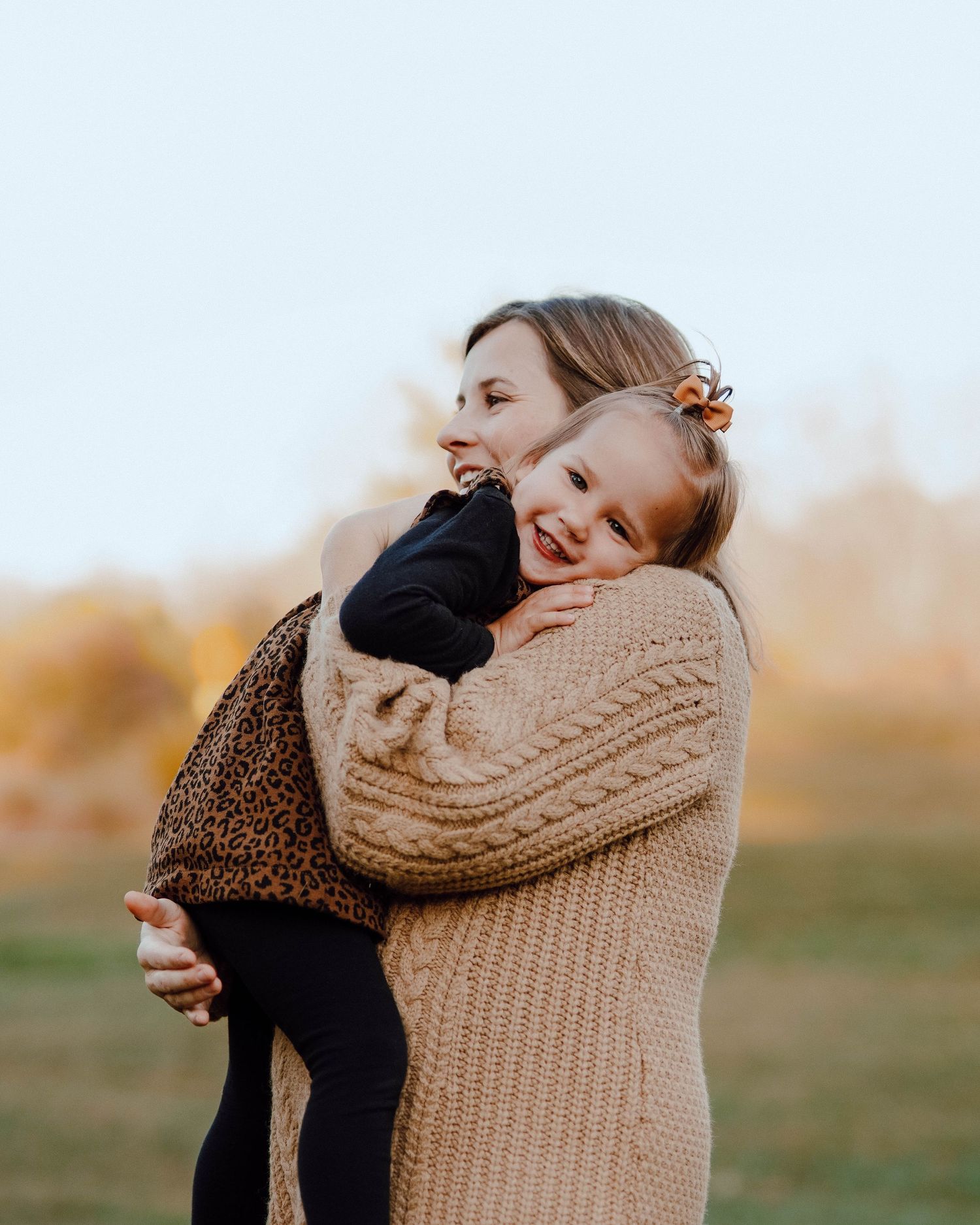 Two people sharing a joyful embrace and laughter together outdoors during autumn golden hour.