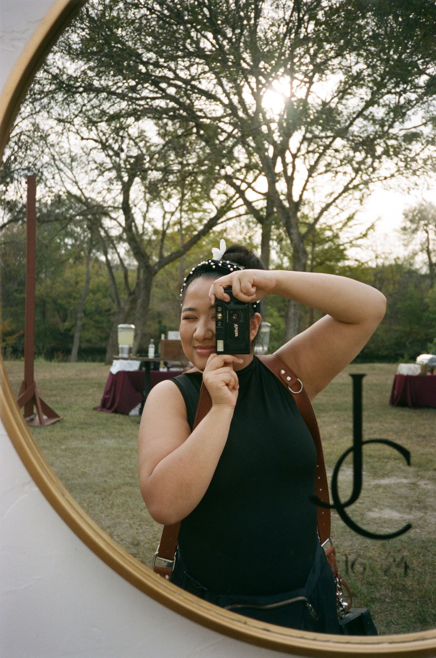 A sequence of mirror selfies shows a person in a dark sleeveless top adjusting their hair in a rustic outdoor setting.