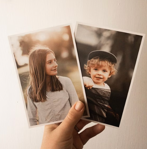 Hand holding two vintage-style portrait photographs against white background.