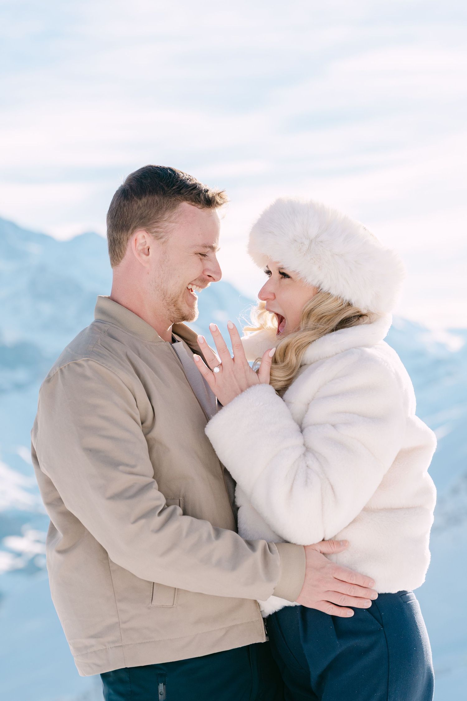 A loving couple shares a joyful moment together in winter against a stunning snowy mountain backdrop.