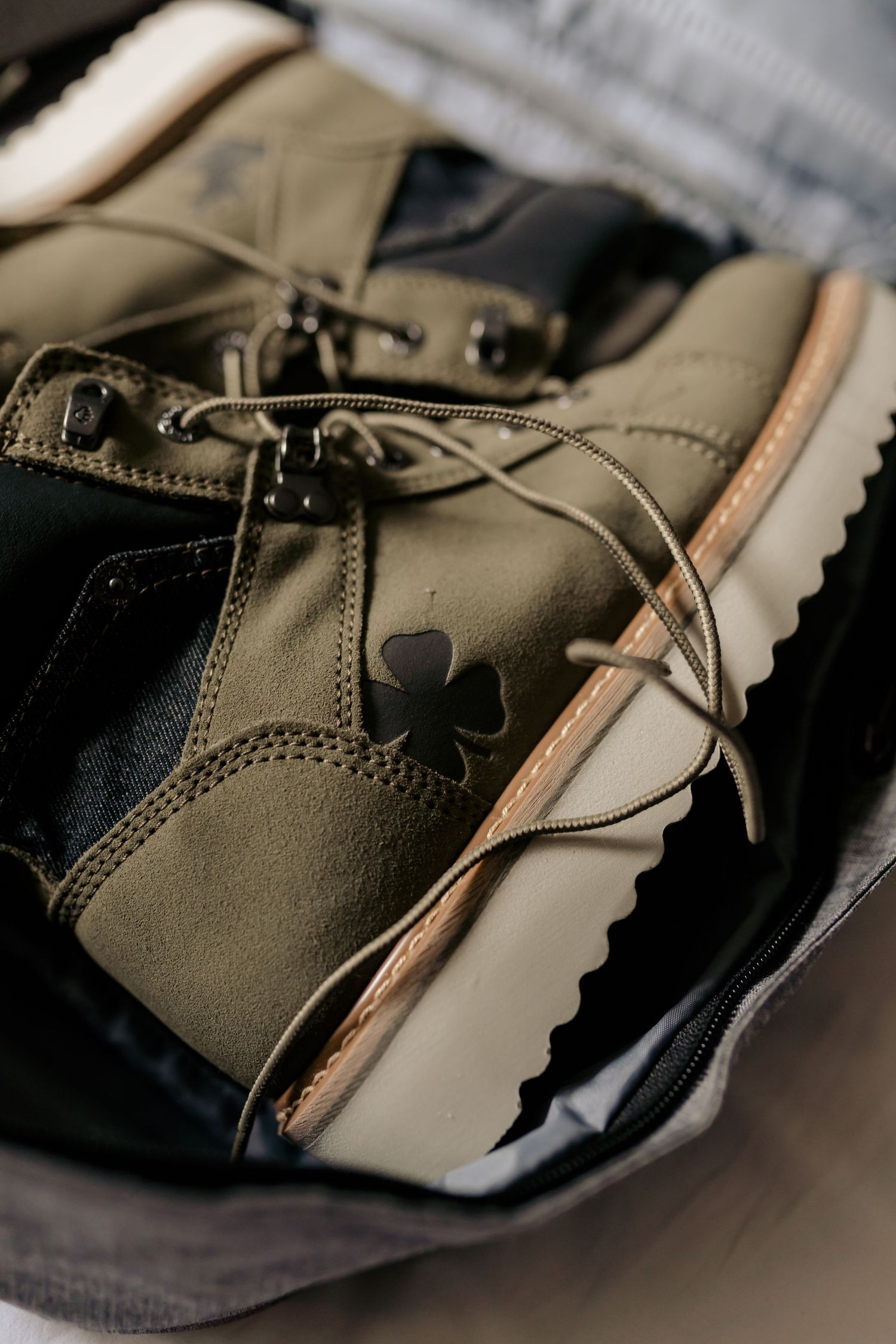 Close-up of olive green leather boot with unique clover detail and white sole.