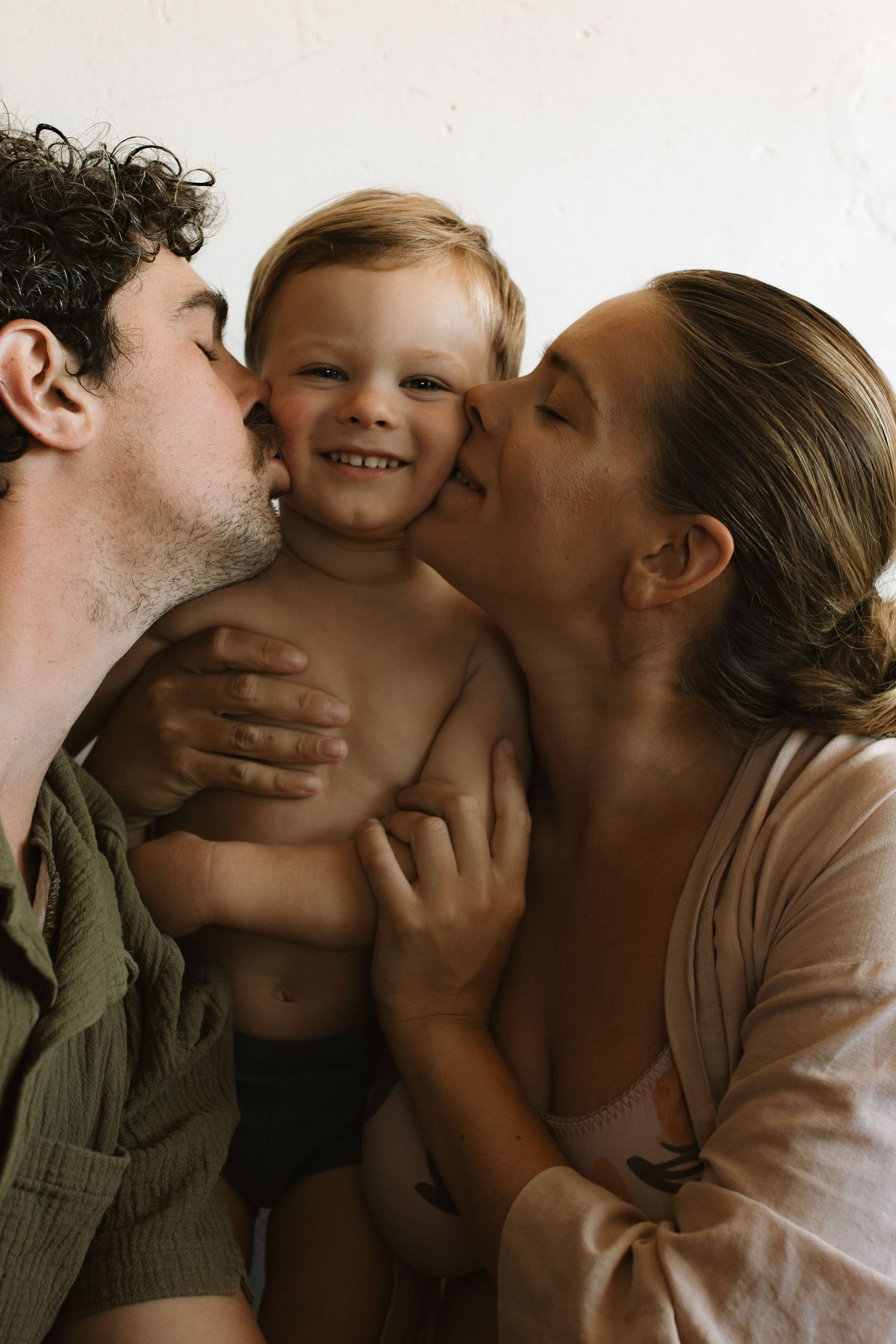Mother and Father kissing their sweet son's cheeks