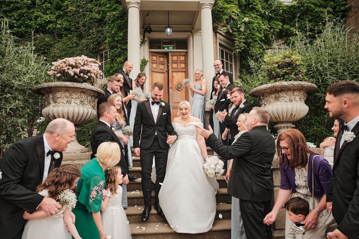 Wedding guests celebrate during outdoor evening reception at Hampton Court House by Jason Leaman Photography a Surrey Wedding Photographer