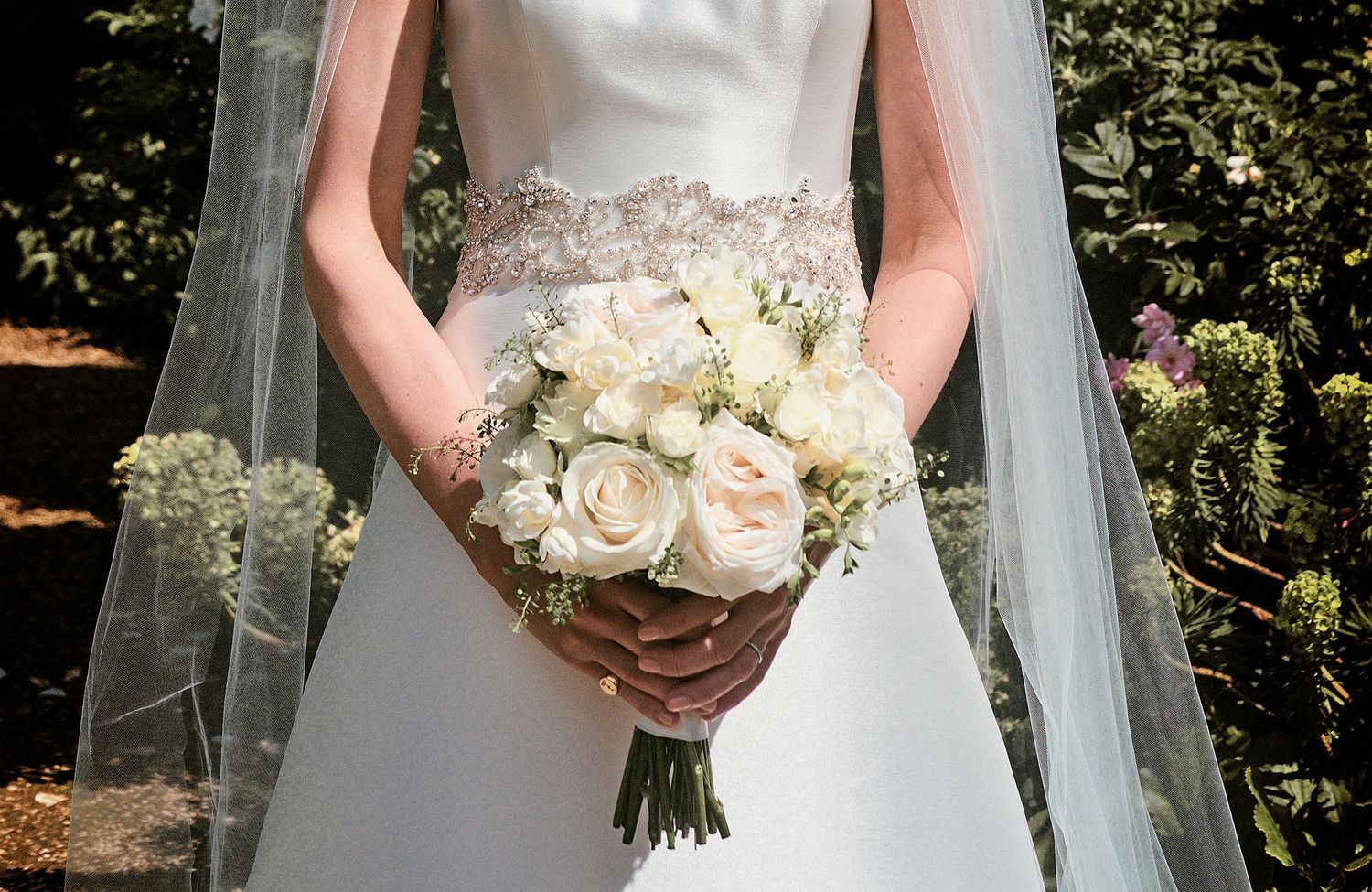 A bridal bouquet of white roses against an ivory wedding dress with delicate beaded detailing, by Surrey Wedding Photographer Jason Leaman
