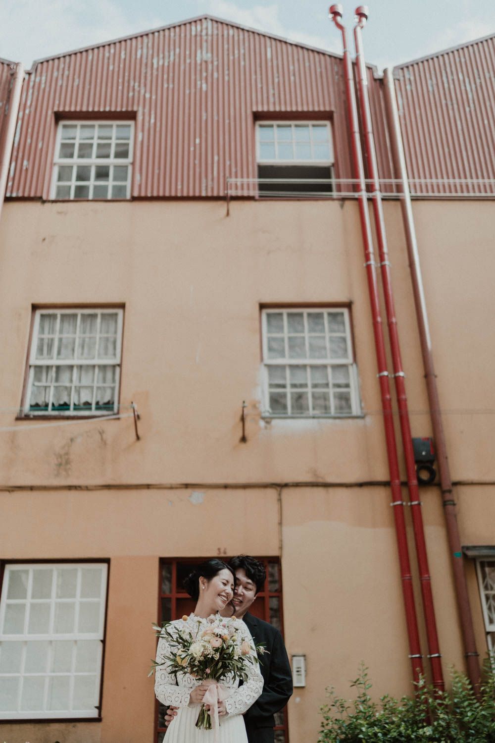 Alternative elopement in Portugal — bride with bouquet standing in front of urban building in Porto