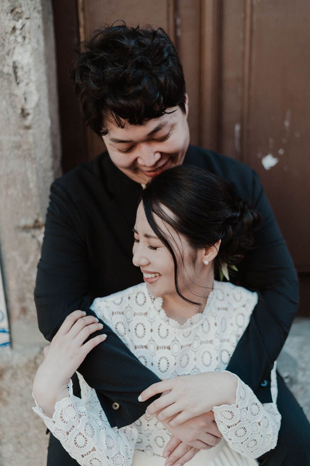 Intimate elopement couple embracing warmly in a rustic Portuguese street — cinematic wedding photography in Porto.