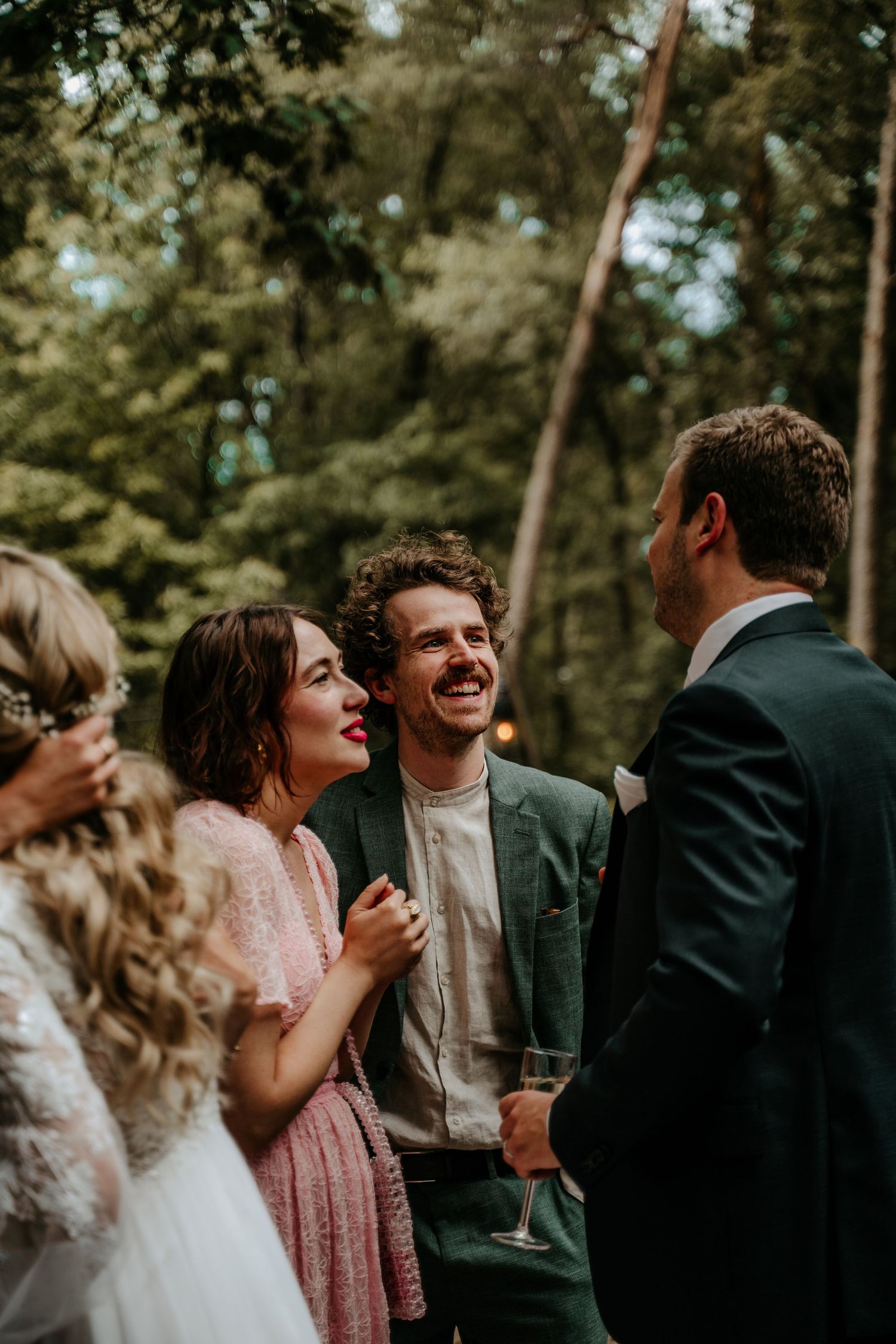 Wedding guests share a joyful moment during an outdoor forest celebration.