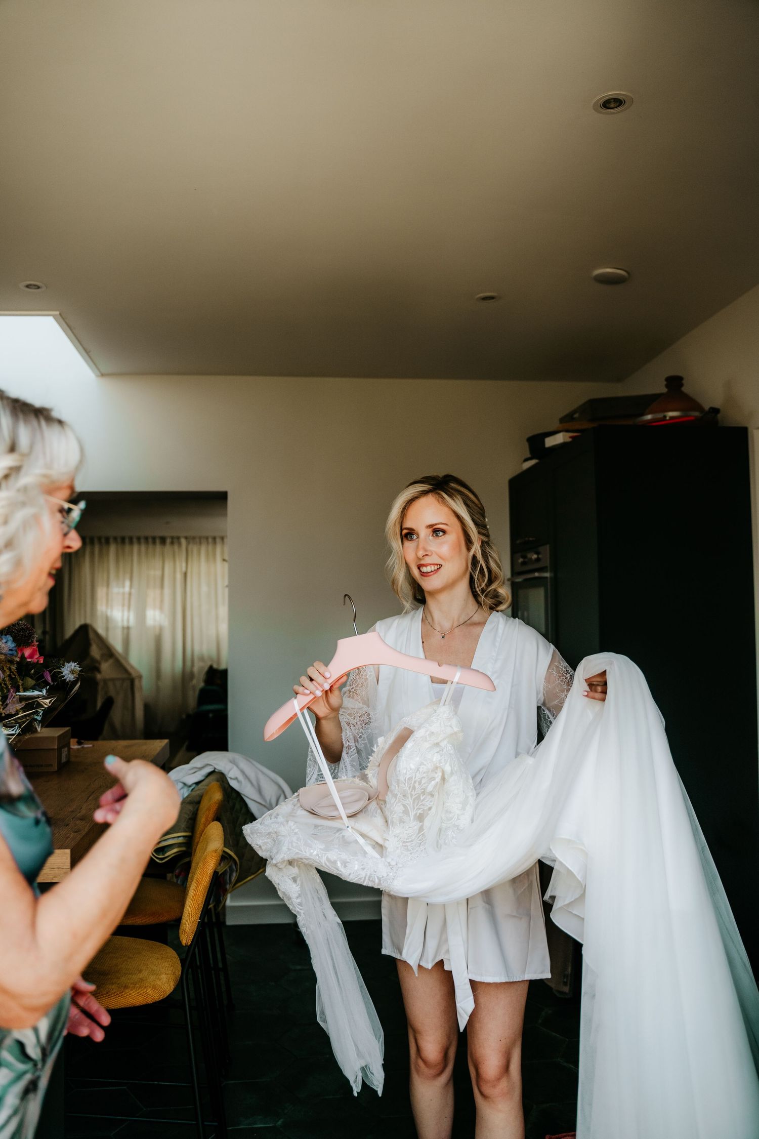 Wedding preparations in a bright room with white dress and robes.