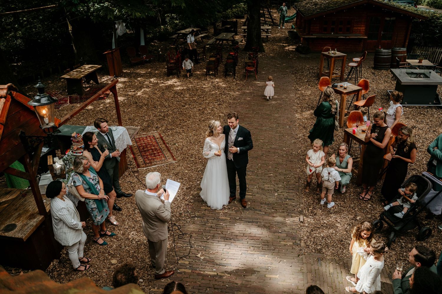 Aerial view of outdoor forest wedding ceremony with guests gathered around.