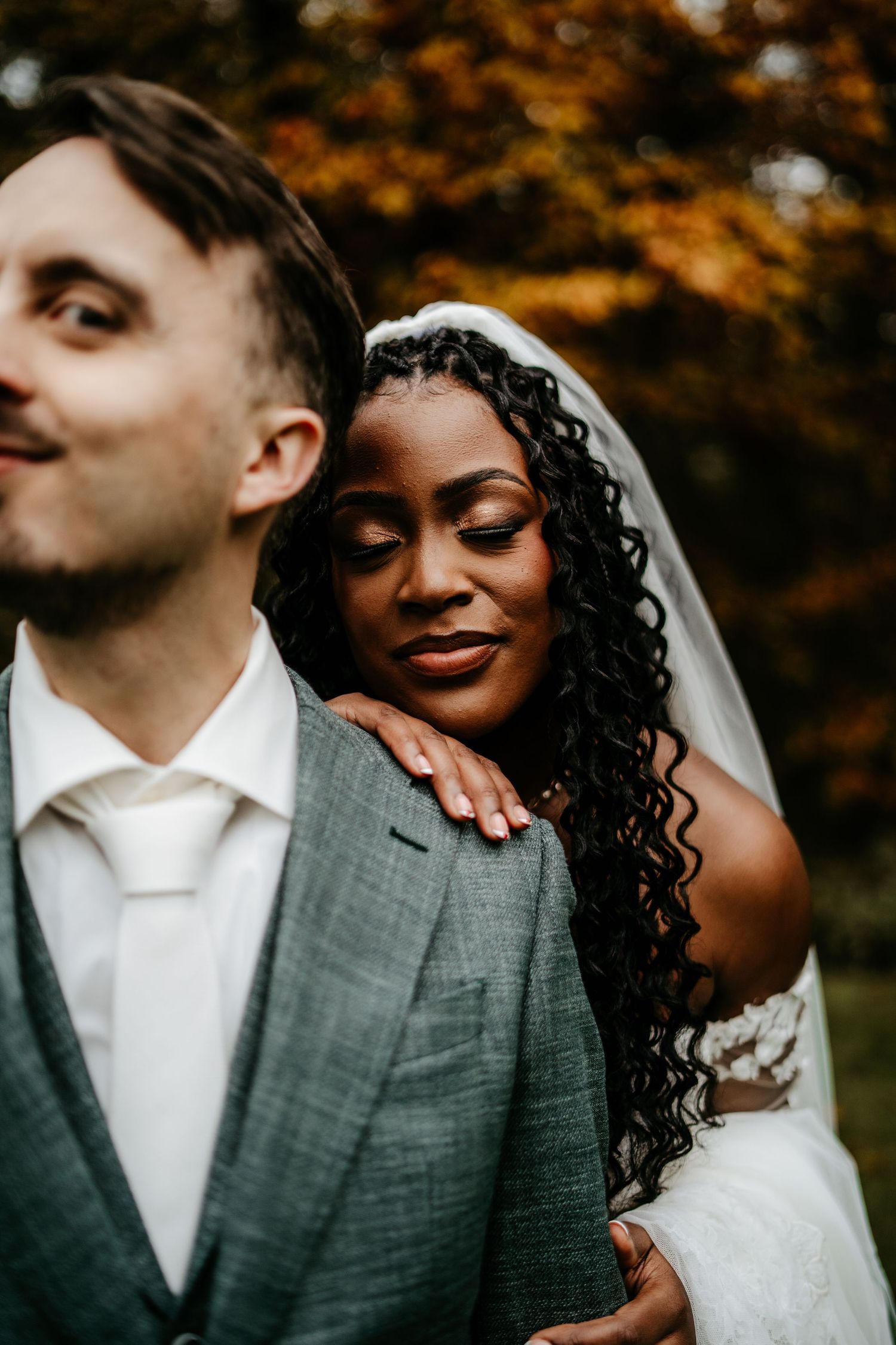 A tender moment between newlyweds against autumn foliage background.