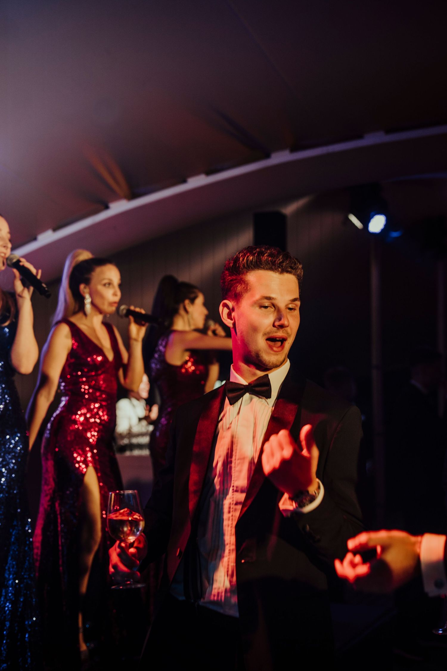 Energetic performers in formal attire singing and entertaining at a wedding reception.