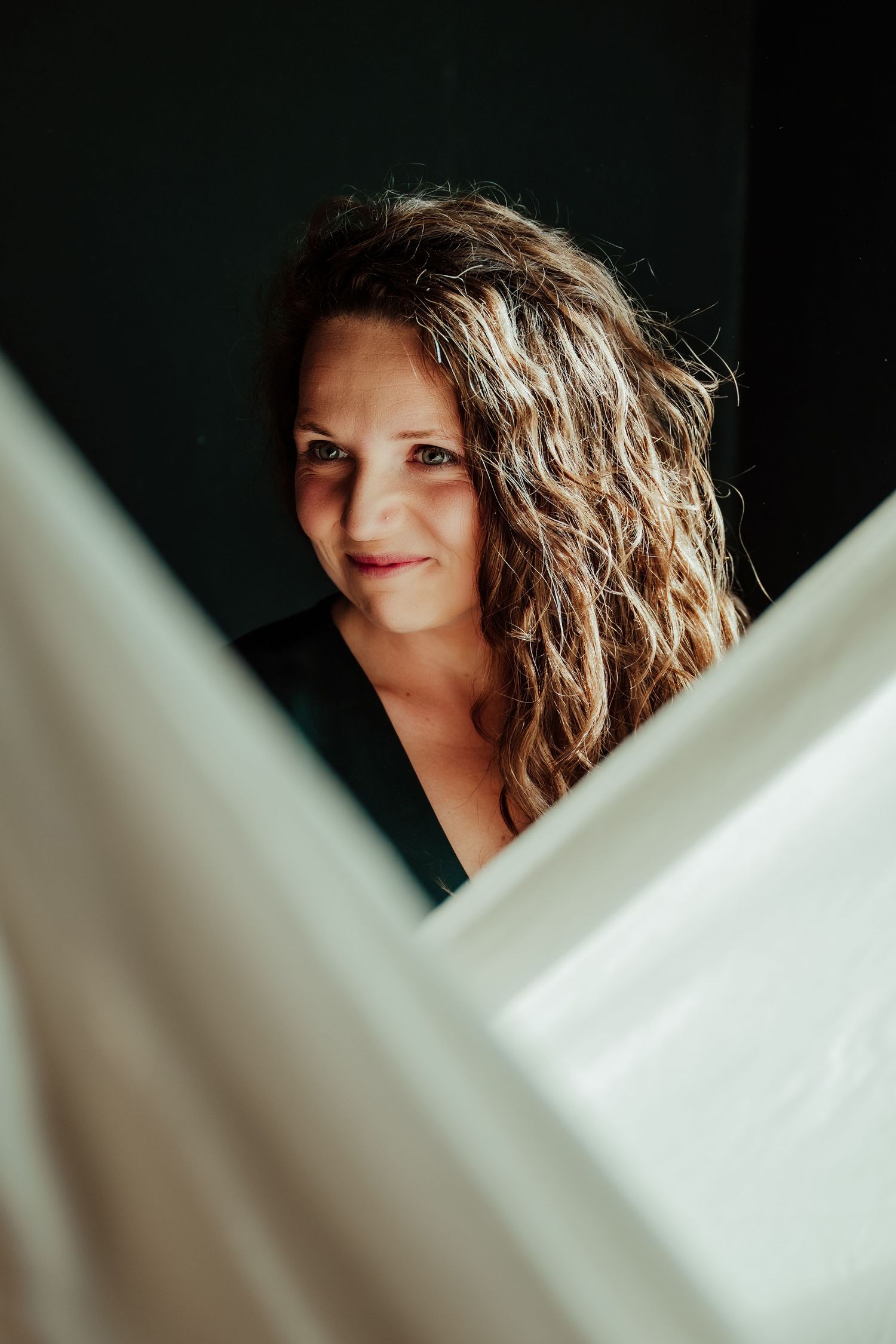 Artistic portrait through white fabric with natural window light.