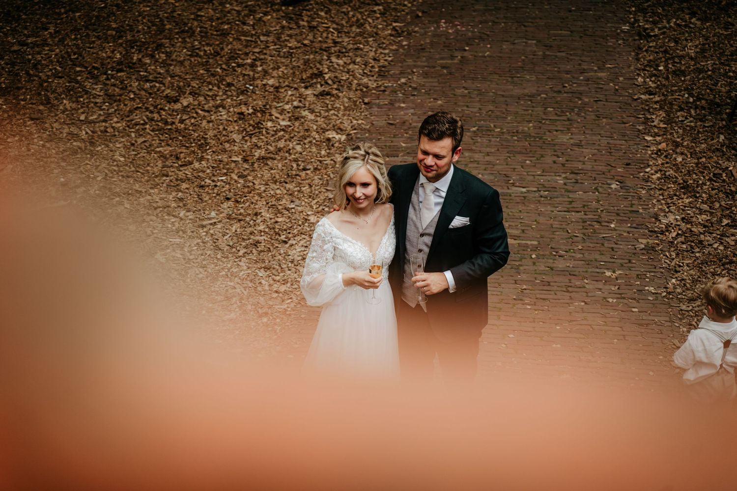 Romantic outdoor wedding moment captured through blurred foreground.